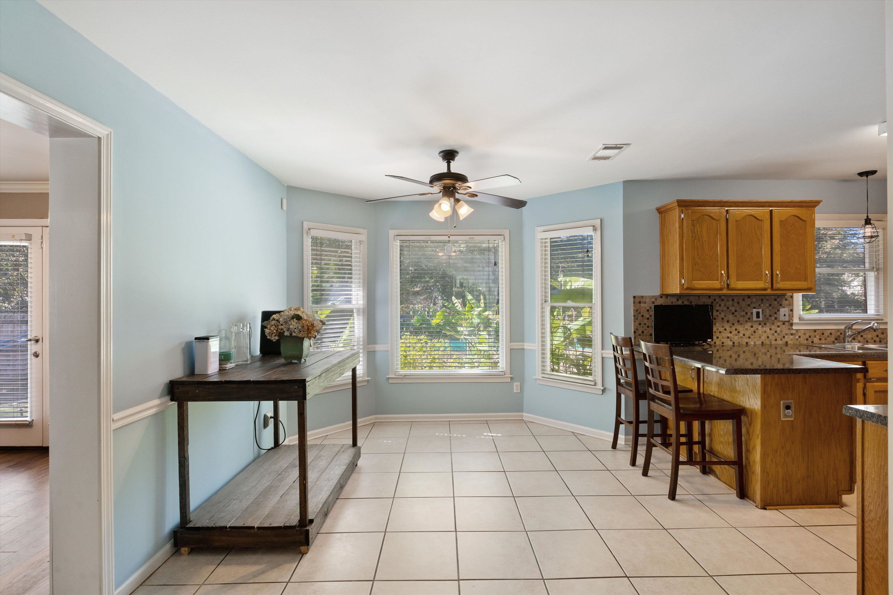 Kitchen featuring decorative backsplash, a breakfast bar, decorative light fixtures, light tile patterned floors, and ceiling fan