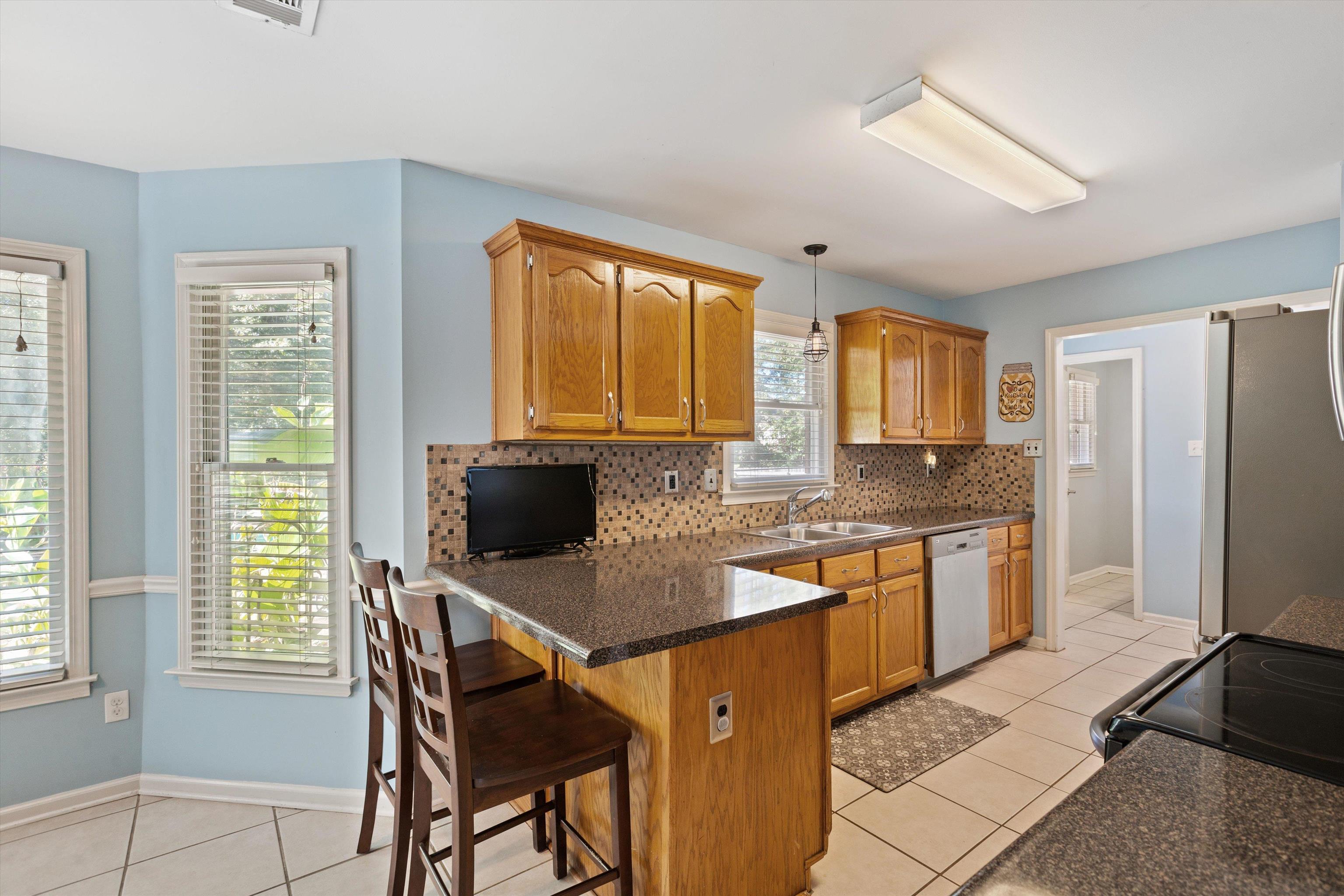Kitchen featuring a wealth of natural light, dishwasher, a kitchen bar, and hanging light fixtures