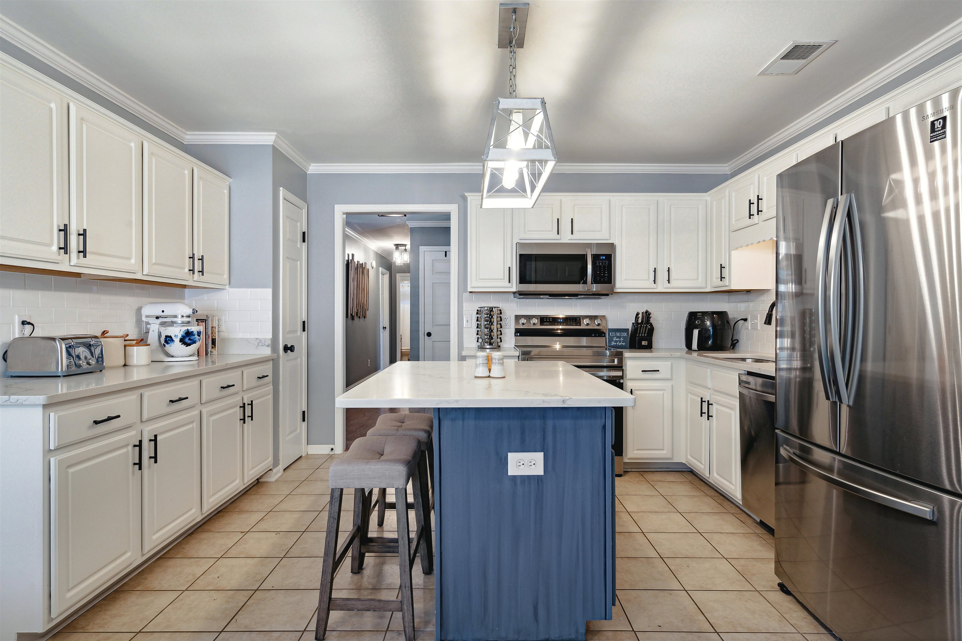 Kitchen with appliances with stainless steel finishes, white cabinetry, a center island, and decorative light fixtures