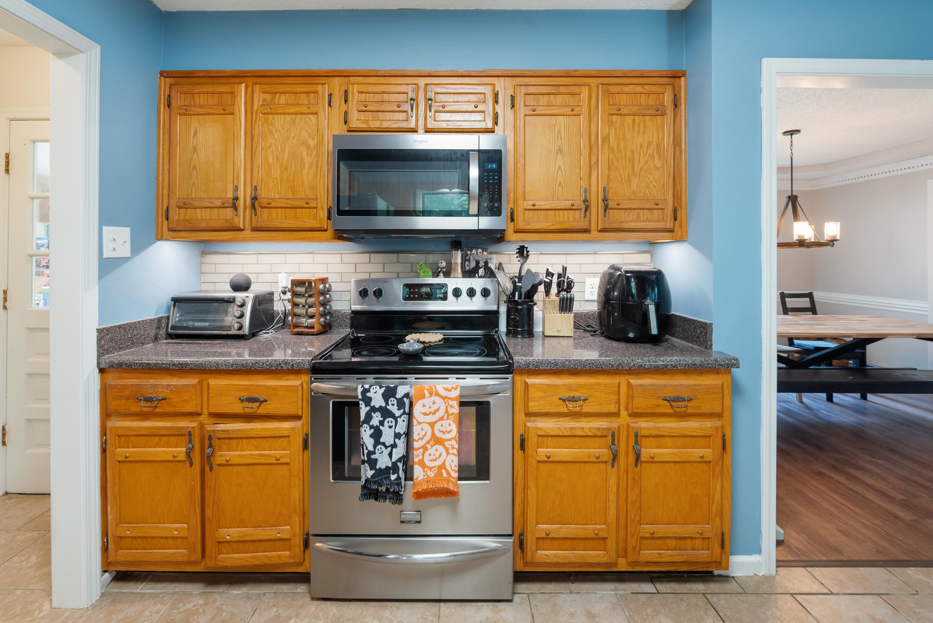 Kitchen featuring appliances with stainless steel finishes, backsplash, crown molding, light hardwood / wood-style flooring, and a chandelier