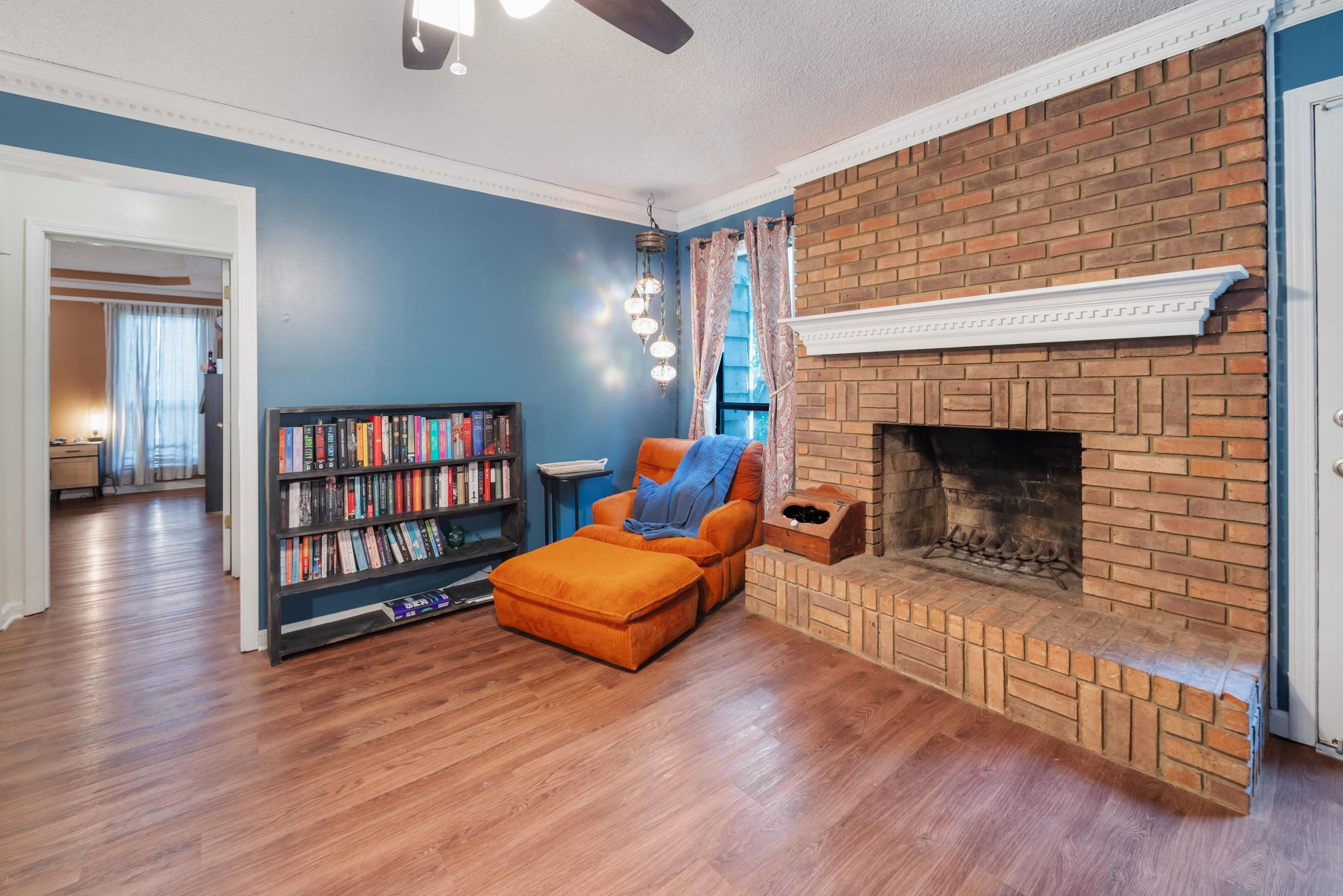 Den featuring ornamental molding, hardwood / wood-style floors, a textured ceiling, and a fireplace