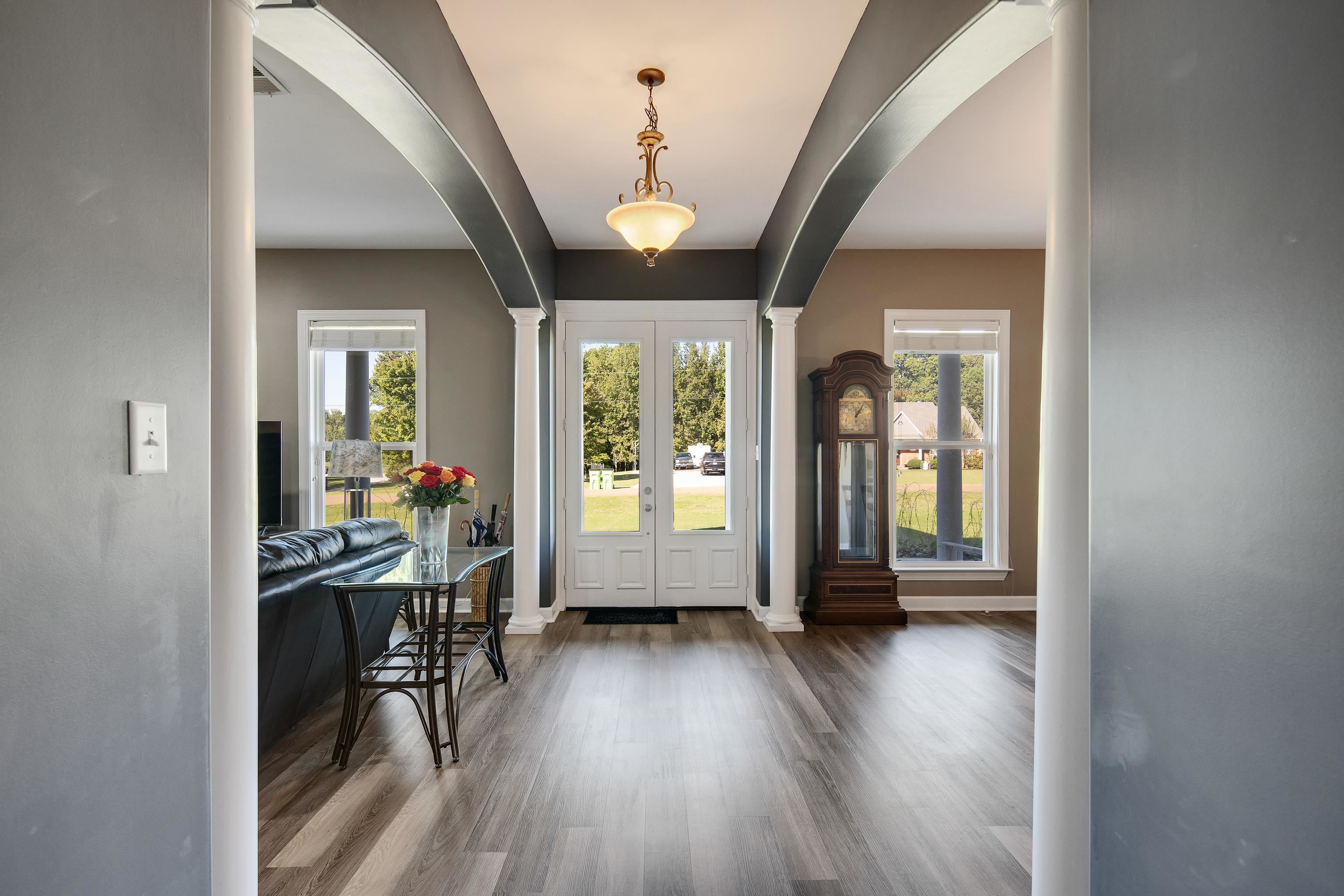 Foyer entrance with decorative columns and hardwood / wood-style floors