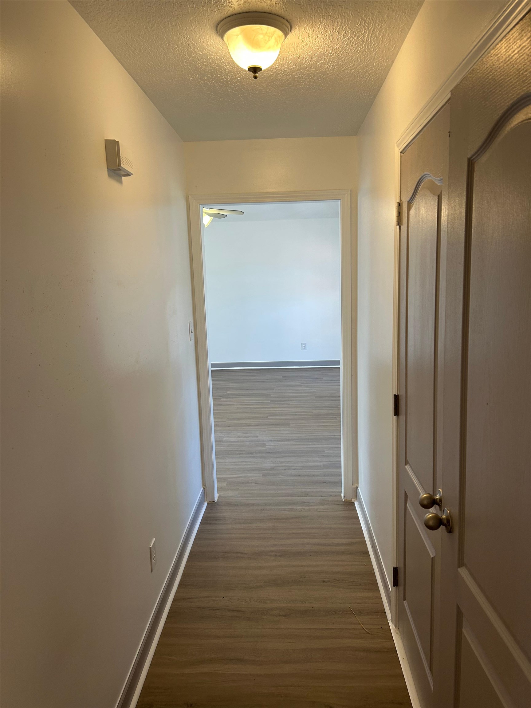 Hall with a textured ceiling and dark hardwood / wood-style floors