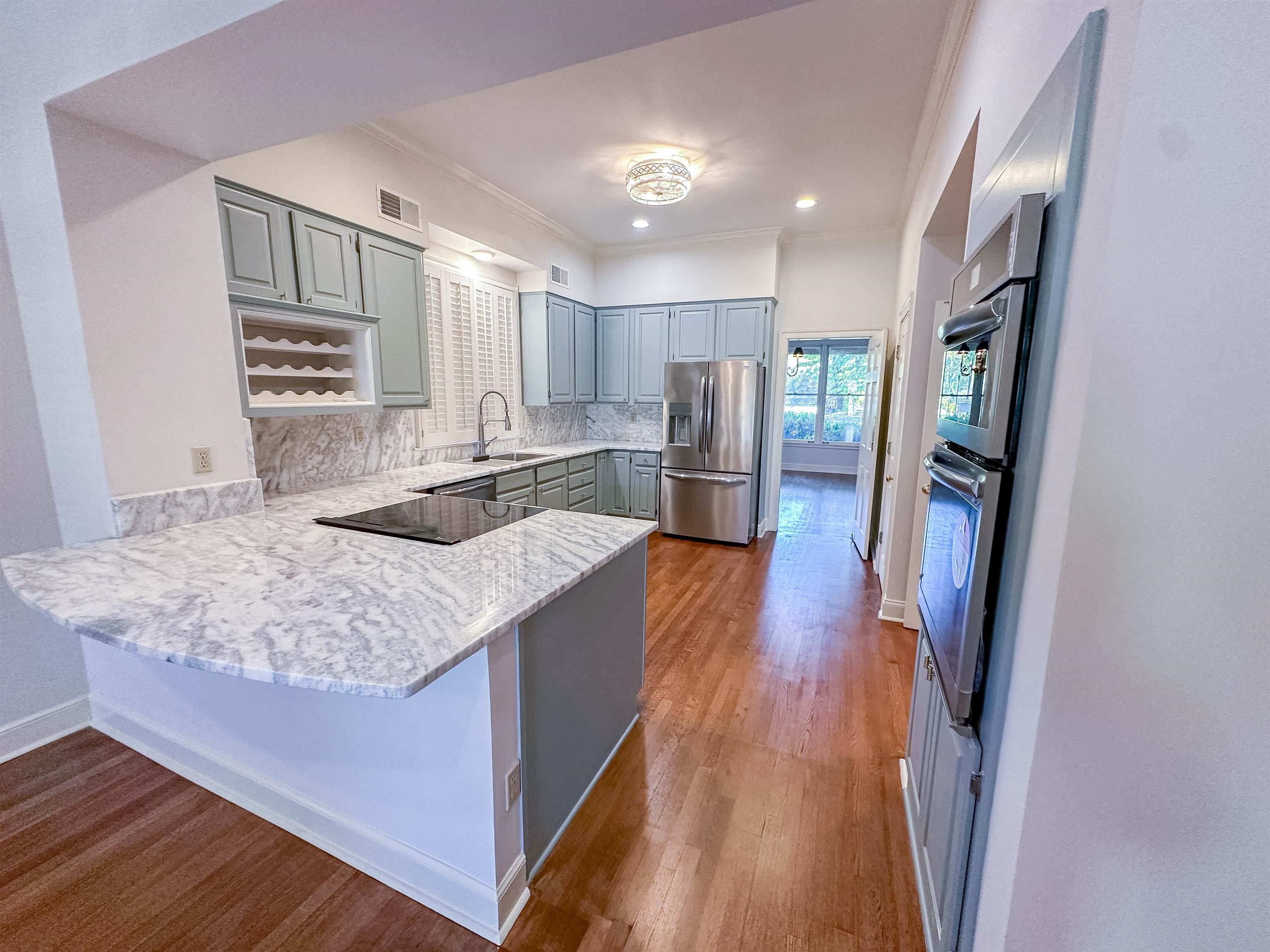 Kitchen with tasteful backsplash, appliances with stainless steel finishes, wood-type flooring, kitchen peninsula, and gray cabinets