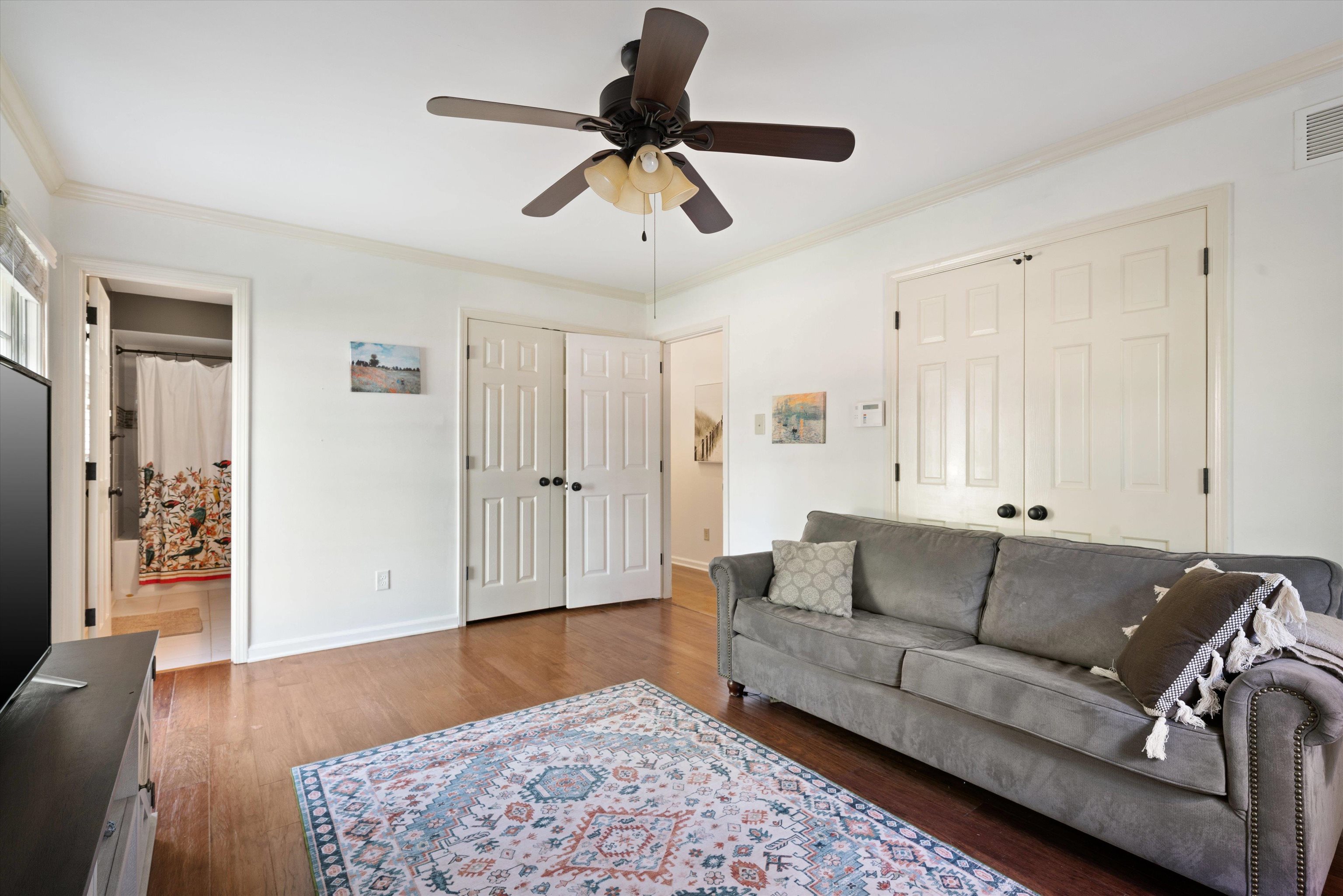 Living room featuring ornamental molding, ceiling fan, and dark hardwood / wood-style floors