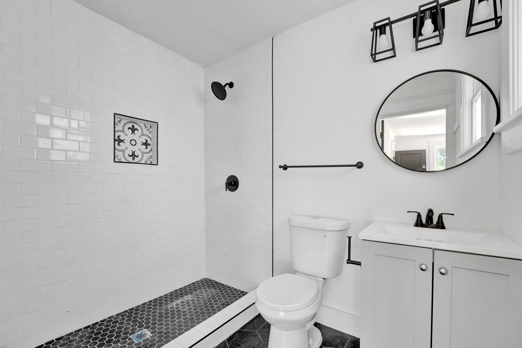 Bathroom featuring a tile shower, toilet, and vanity