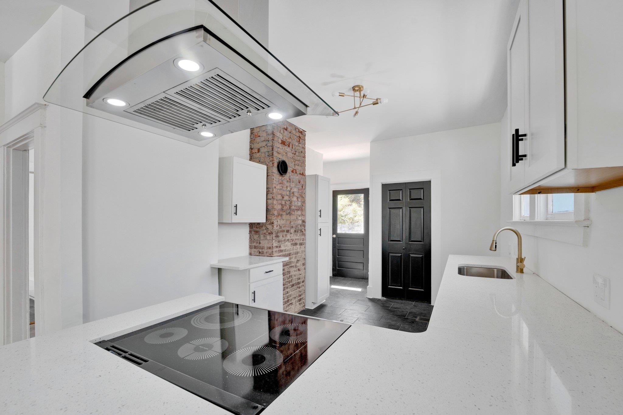Kitchen featuring white cabinetry, island range hood, sink, black electric stovetop, and light stone counters