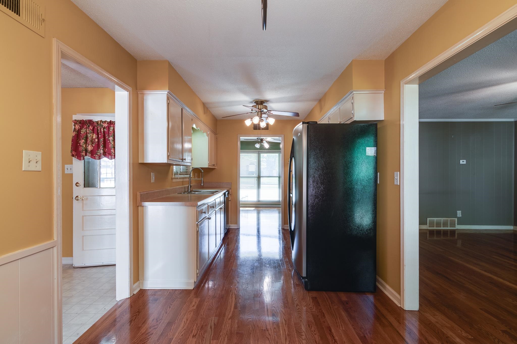 Kitchen featuring dark hardwood / wood-style floors, sink, white cabinetry, stainless steel refrigerator, and ceiling fan