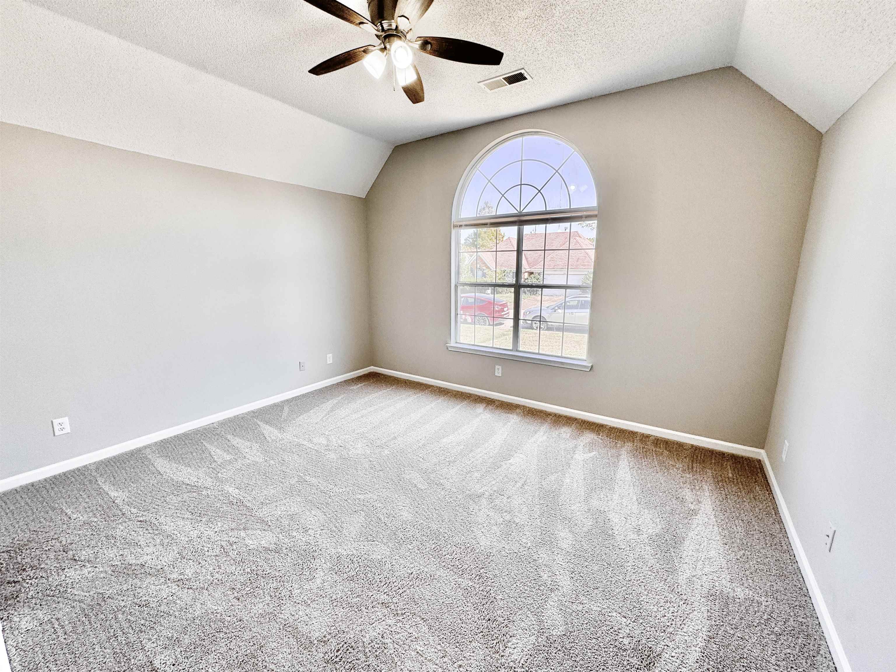 Carpeted empty room featuring ceiling fan, a textured ceiling, and lofted ceiling