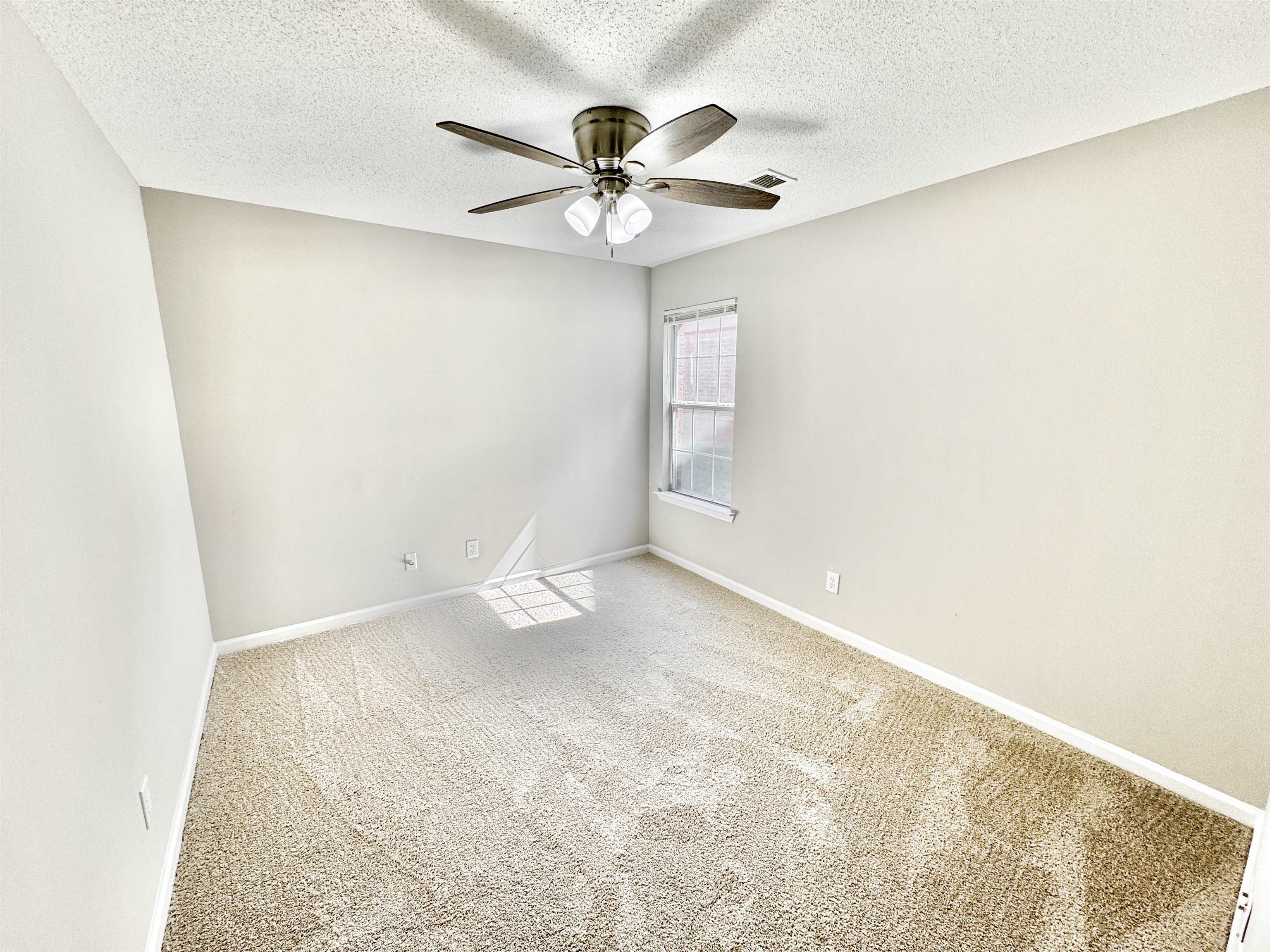 Carpeted empty room with a textured ceiling and ceiling fan