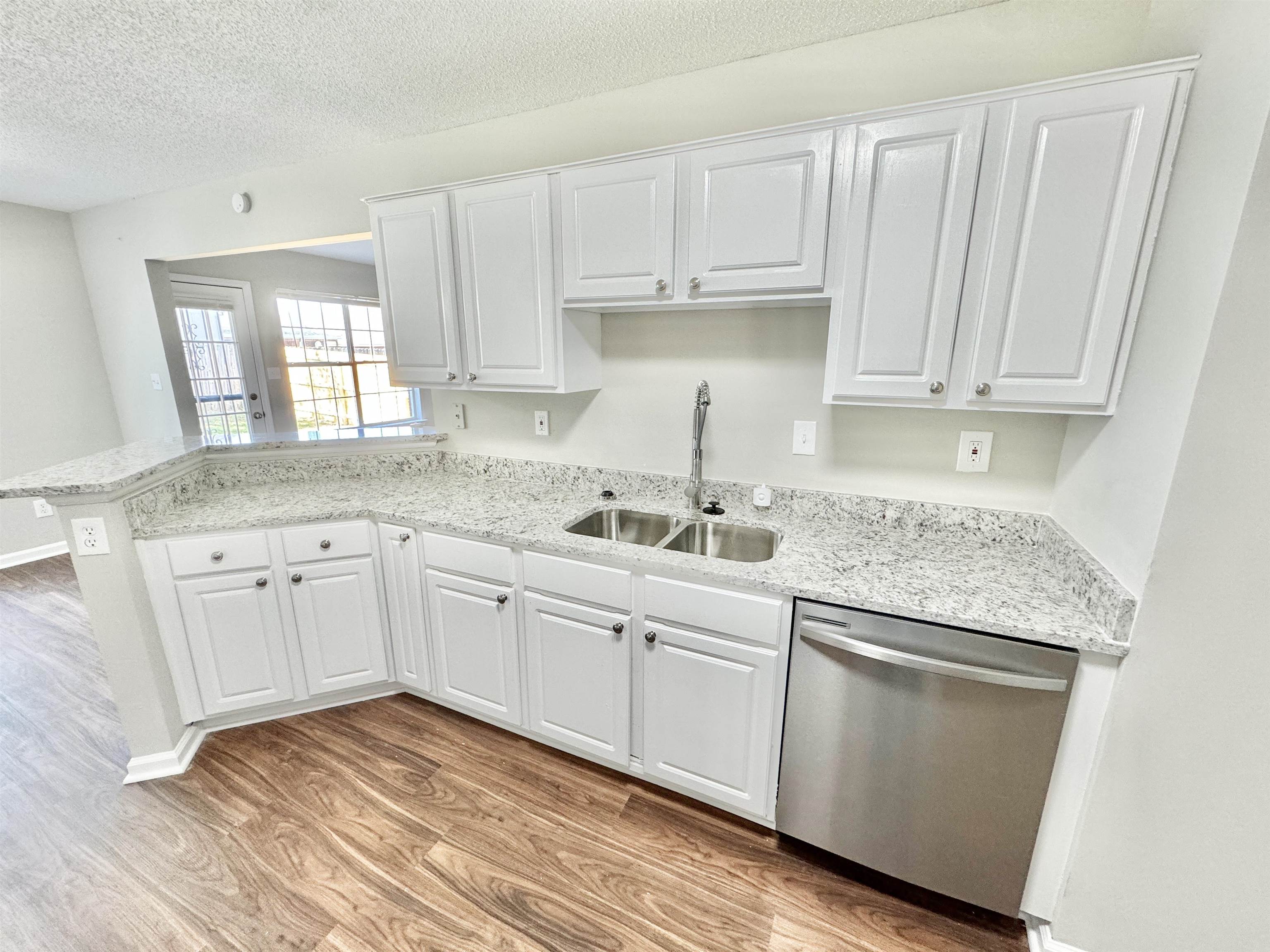 Kitchen with white cabinetry, sink, and stainless steel dishwasher