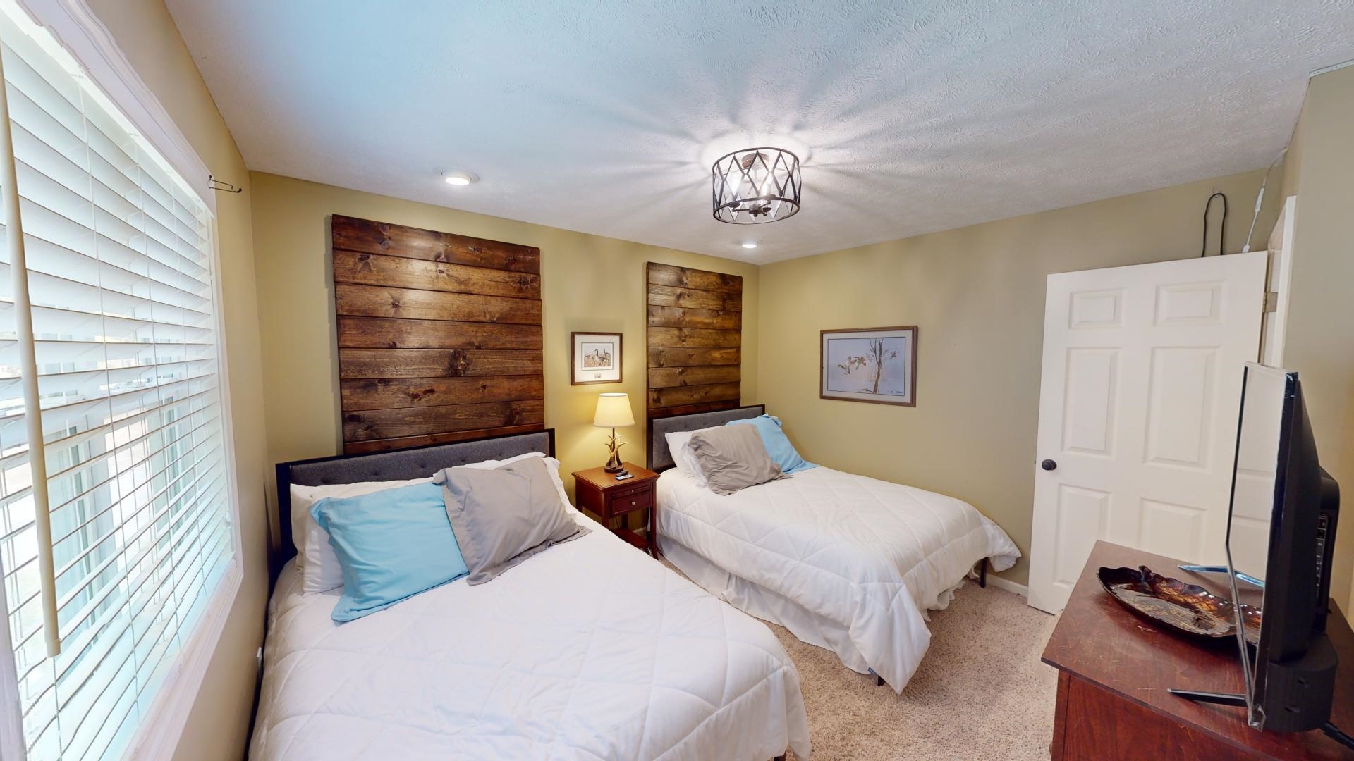 Bedroom featuring a textured ceiling, multiple windows, a chandelier, and light colored carpet