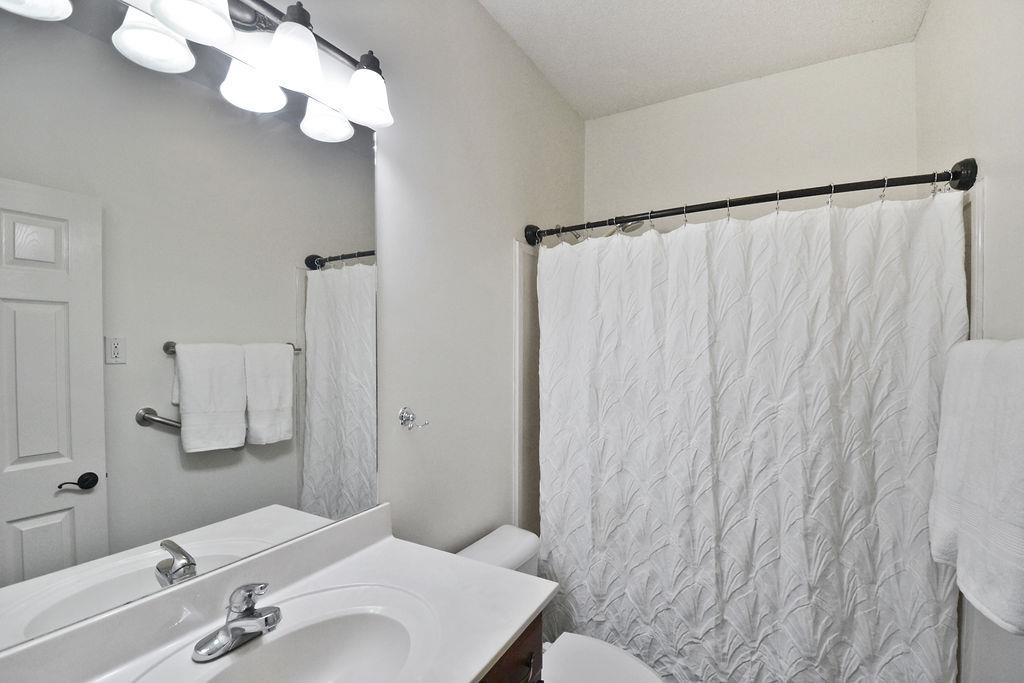 Bathroom with vanity, toilet, a textured ceiling, and curtained shower