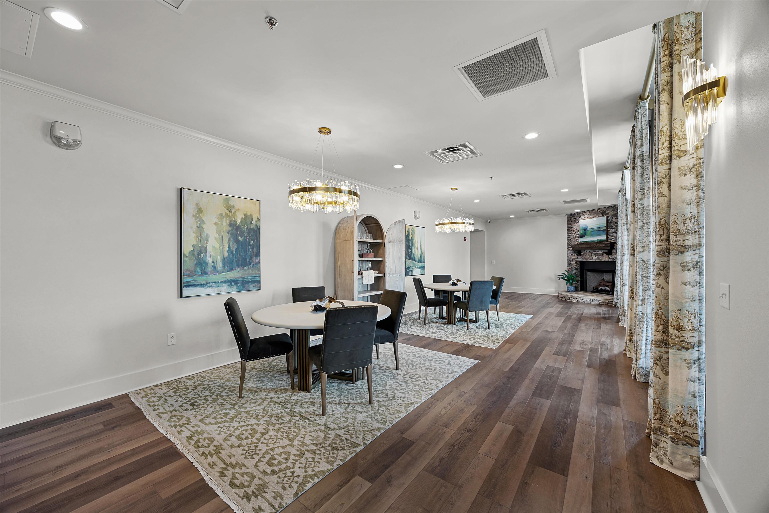 Dining space with an inviting chandelier, hardwood / wood-style flooring, a fireplace, and ornamental molding