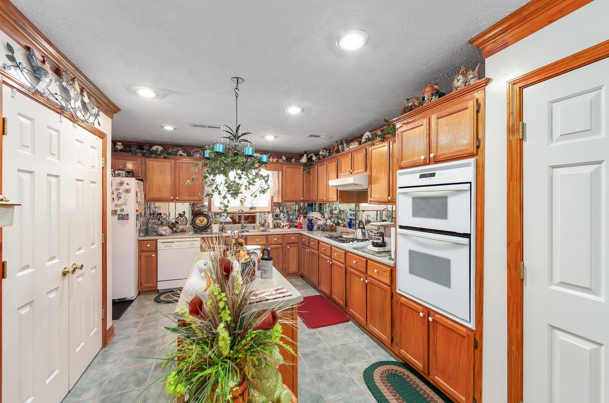 Kitchen featuring white appliances, light tile patterned flooring, backsplash, a textured ceiling, and pendant lighting