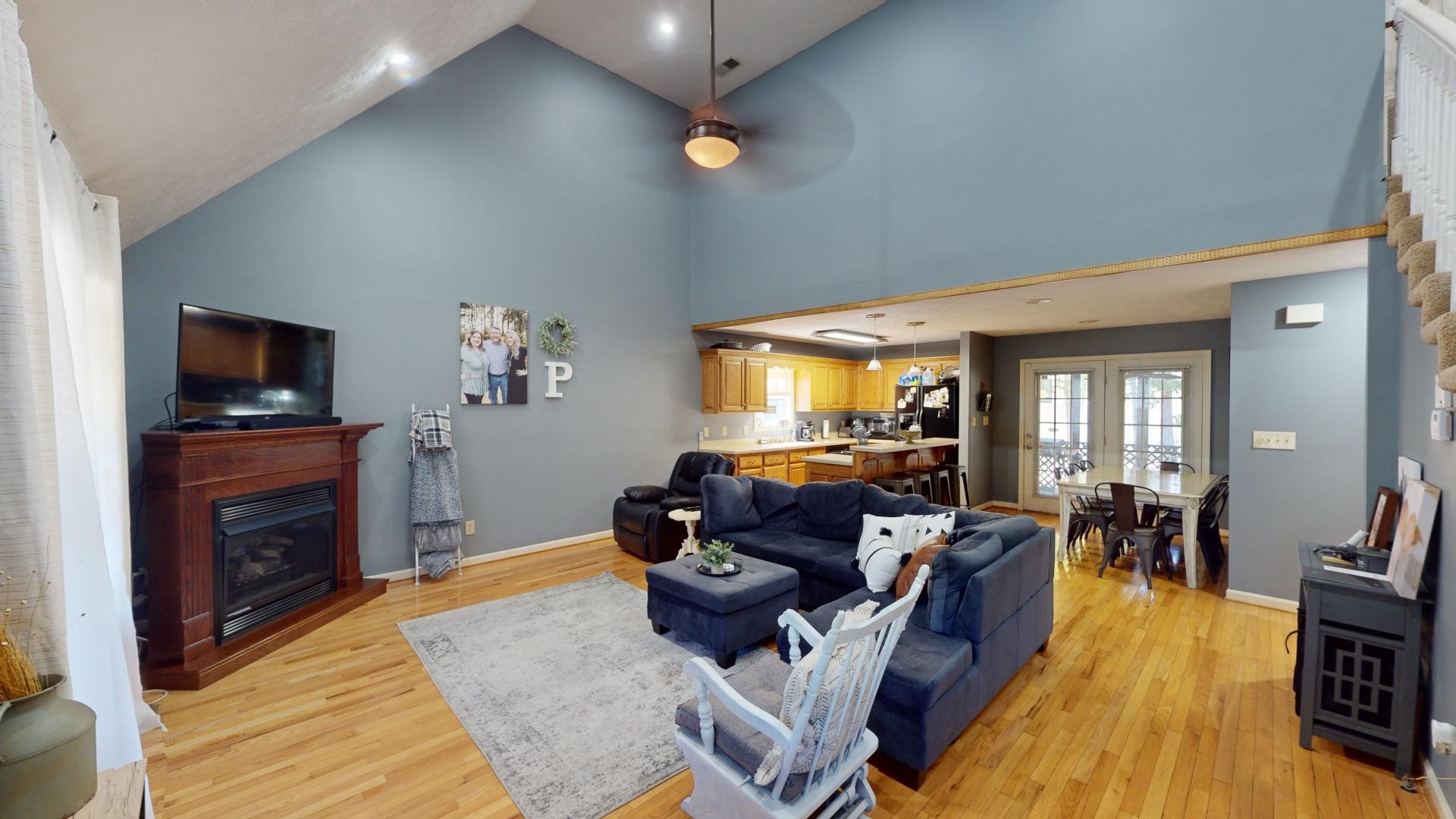 Living room with high vaulted ceiling, light wood-type flooring, and ceiling fan