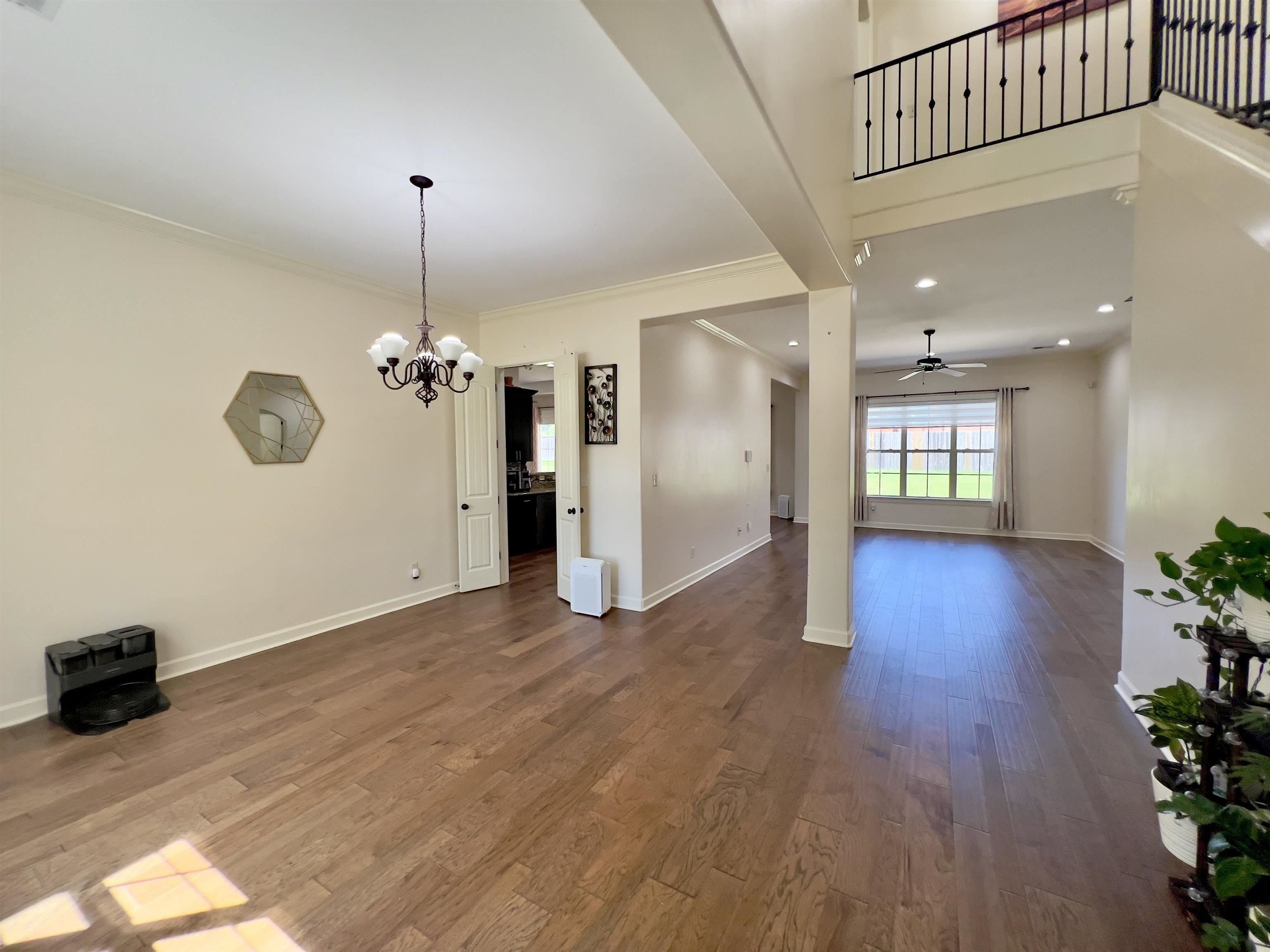 Interior space featuring ornamental molding, dark wood-type flooring, and ceiling fan with notable chandelier