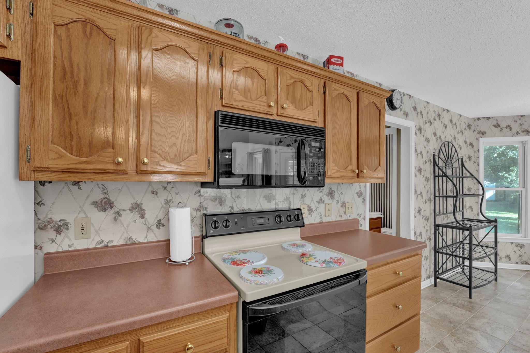 Kitchen featuring range with electric cooktop, a textured ceiling, and light tile patterned flooring