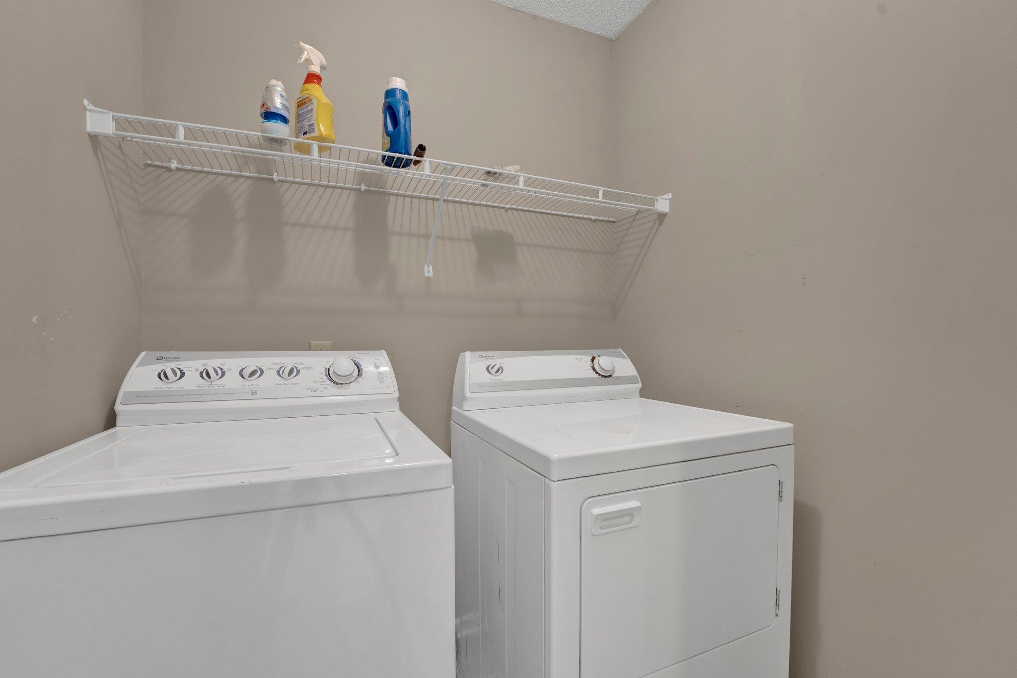 Clothes washing area with washer and clothes dryer and a textured ceiling