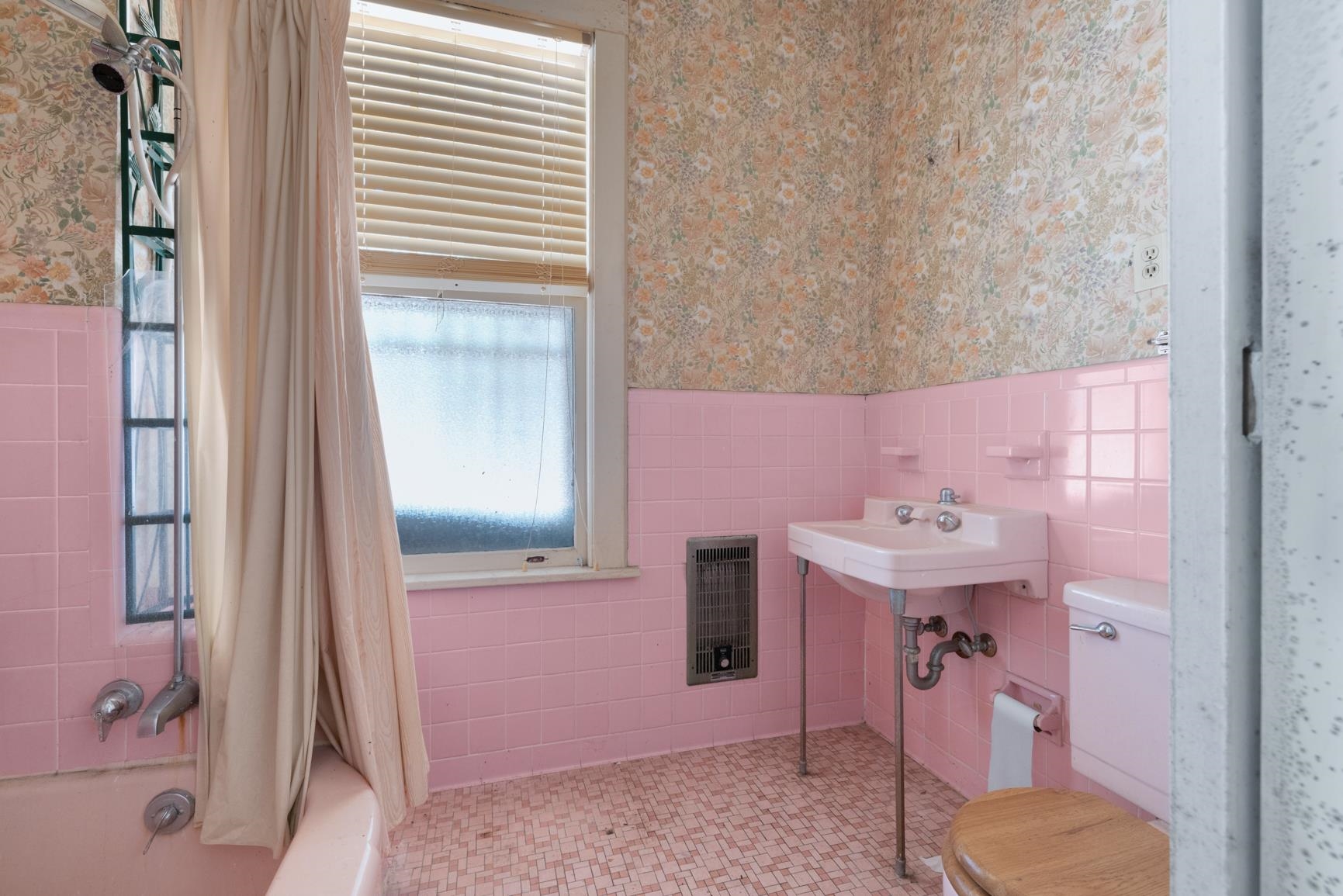 Bathroom featuring toilet, shower / bathtub combination with curtain, heating unit, and tile walls