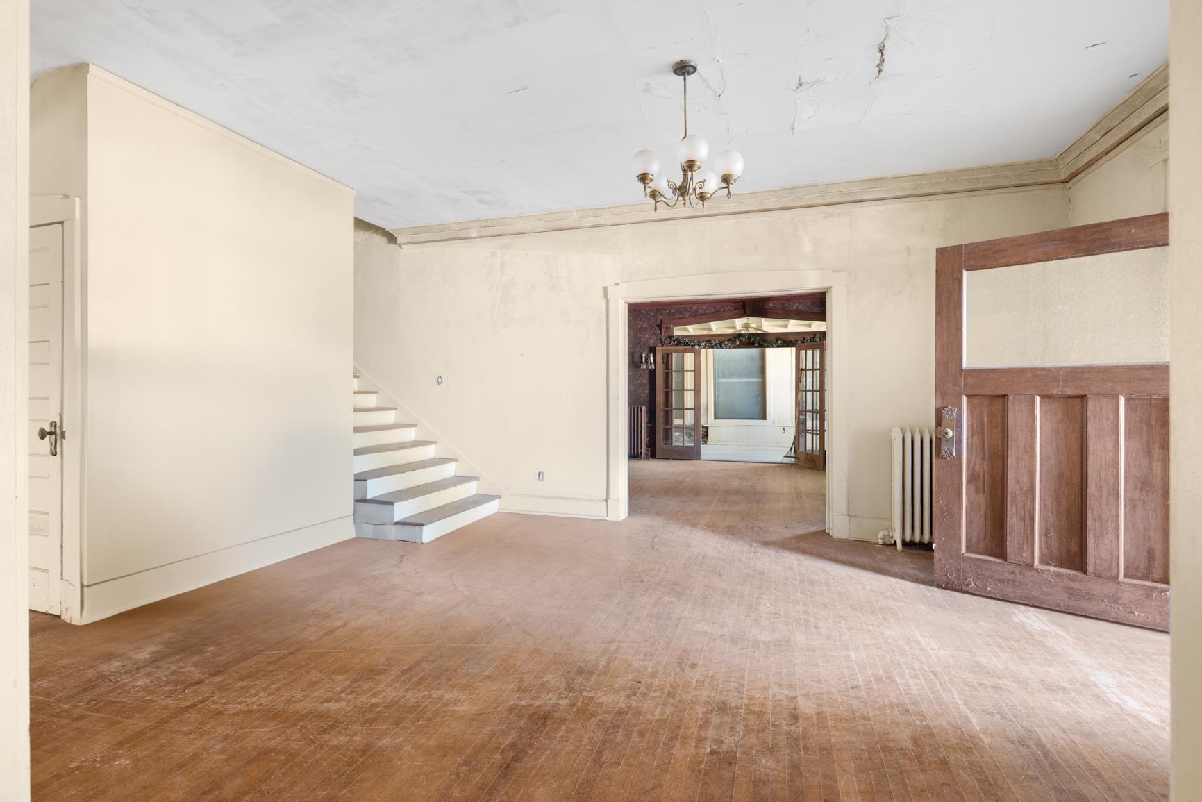 Empty room featuring an inviting chandelier, hardwood / wood-style floors, and radiator