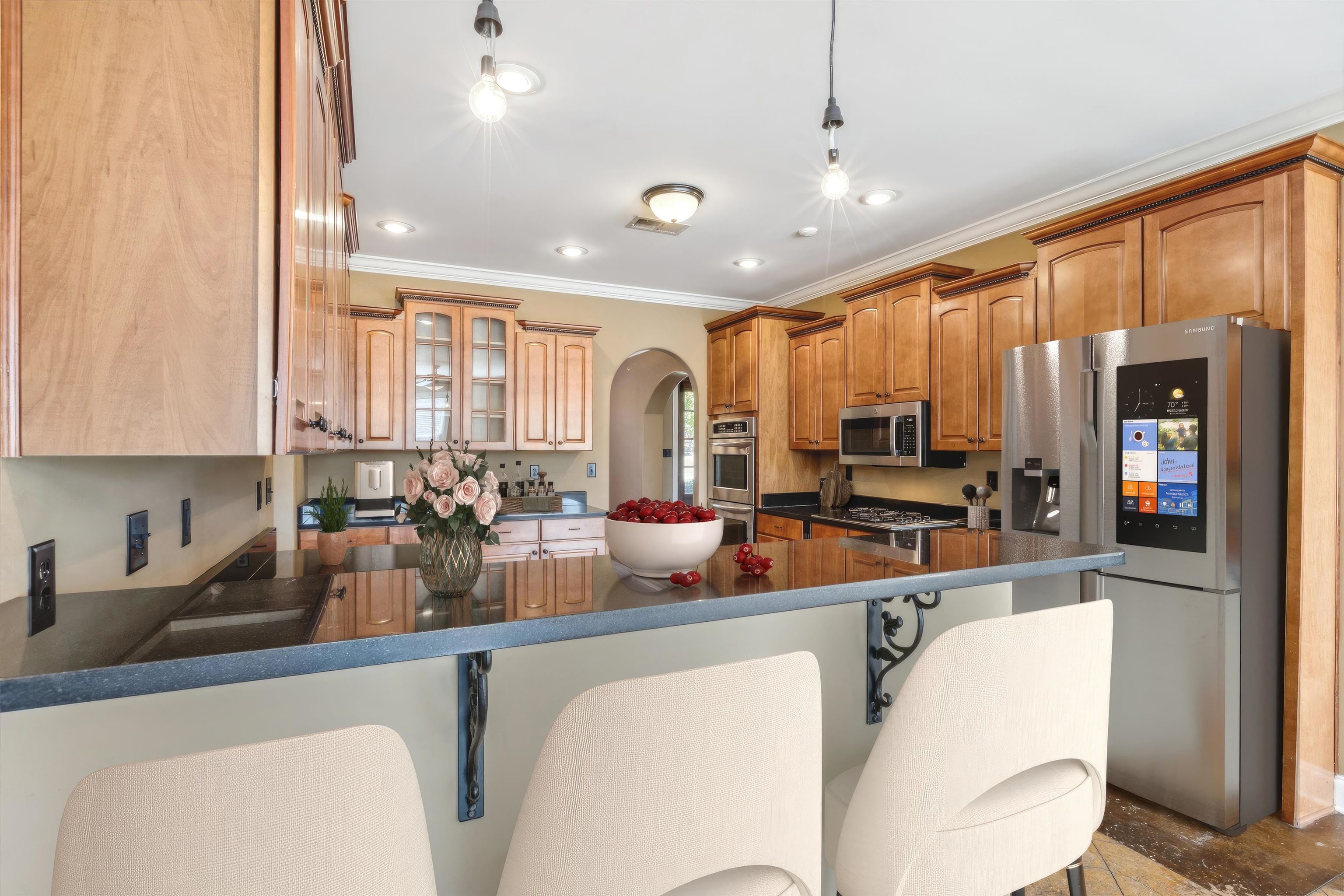 Kitchen featuring kitchen peninsula, a breakfast bar, wood-type flooring, ornamental molding, and stainless steel appliances