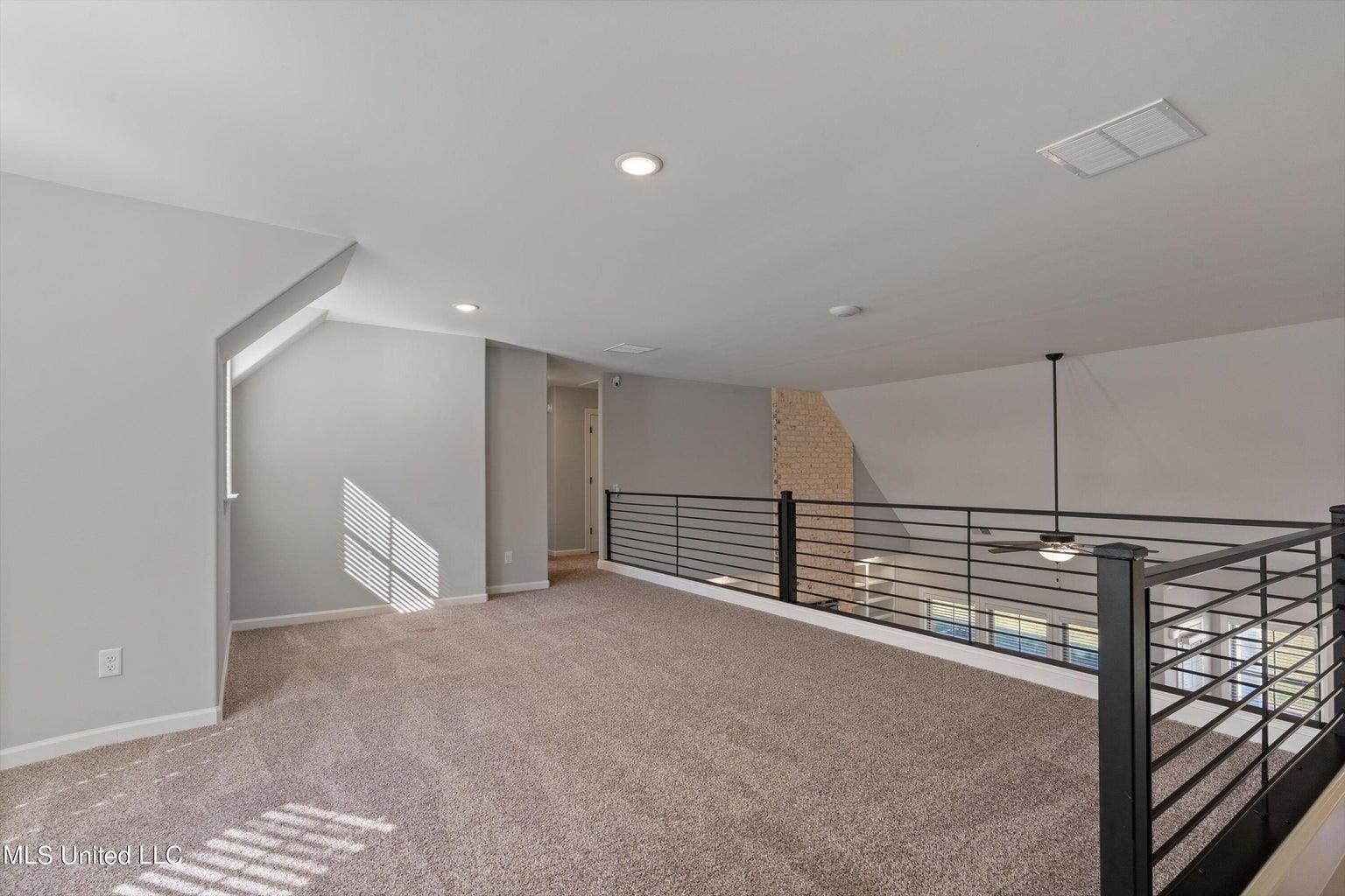 Additional living space featuring ceiling fan, carpet flooring, and lofted ceiling