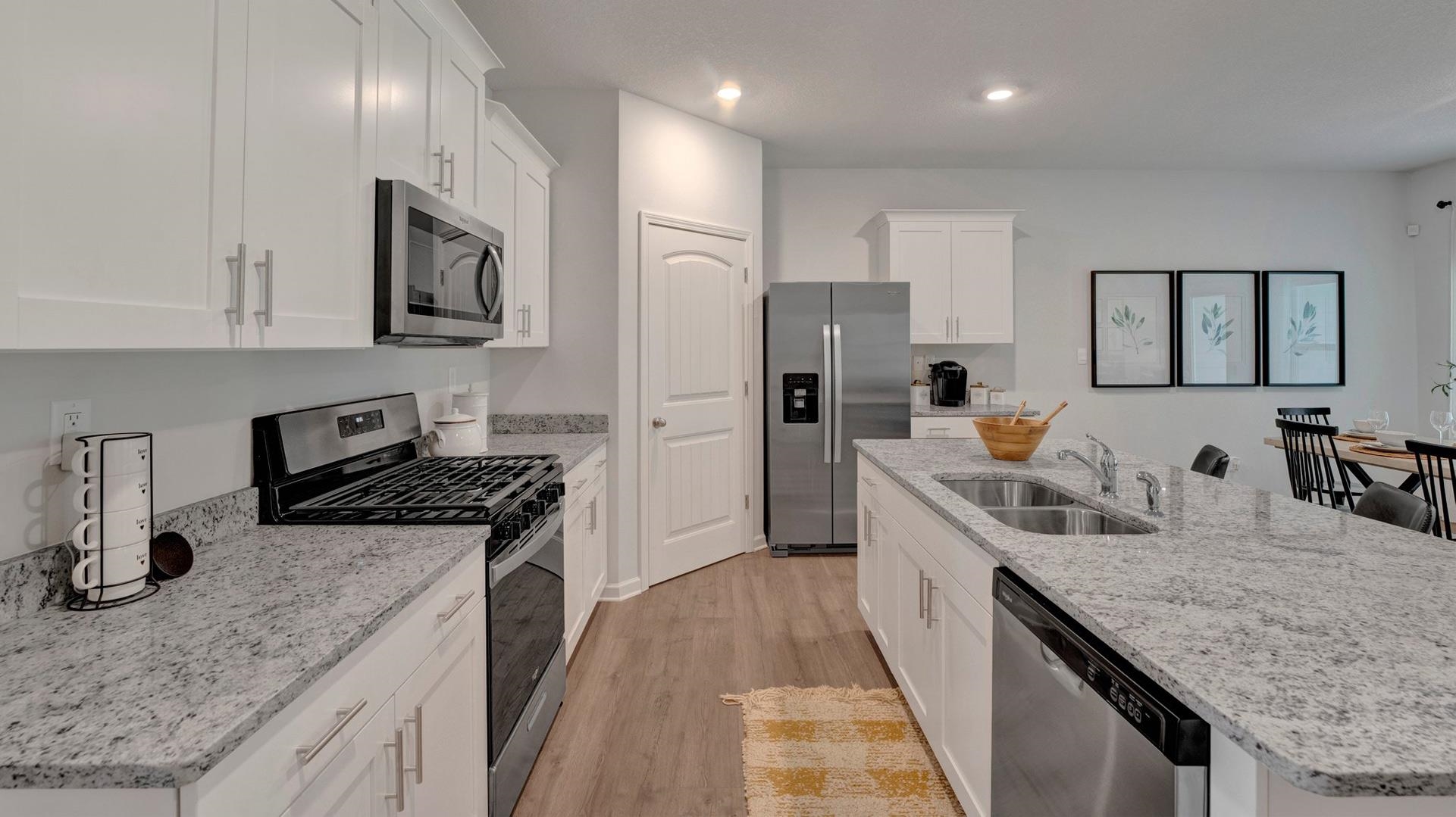 Kitchen with light hardwood / wood-style floors, an island with sink, white cabinets, stainless steel appliances, and sink