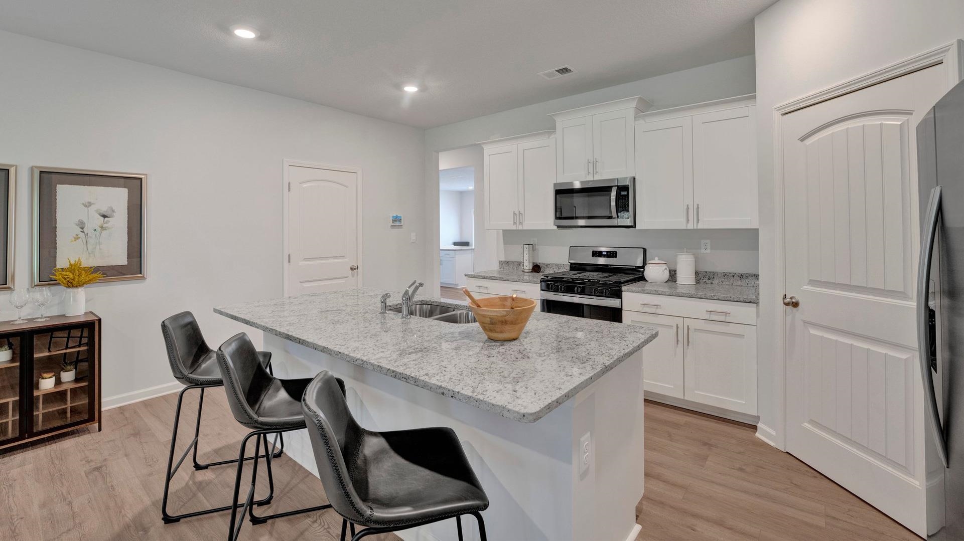 Kitchen with light stone counters, light hardwood / wood-style floors, a kitchen island with sink, white cabinetry, and appliances with stainless steel finishes