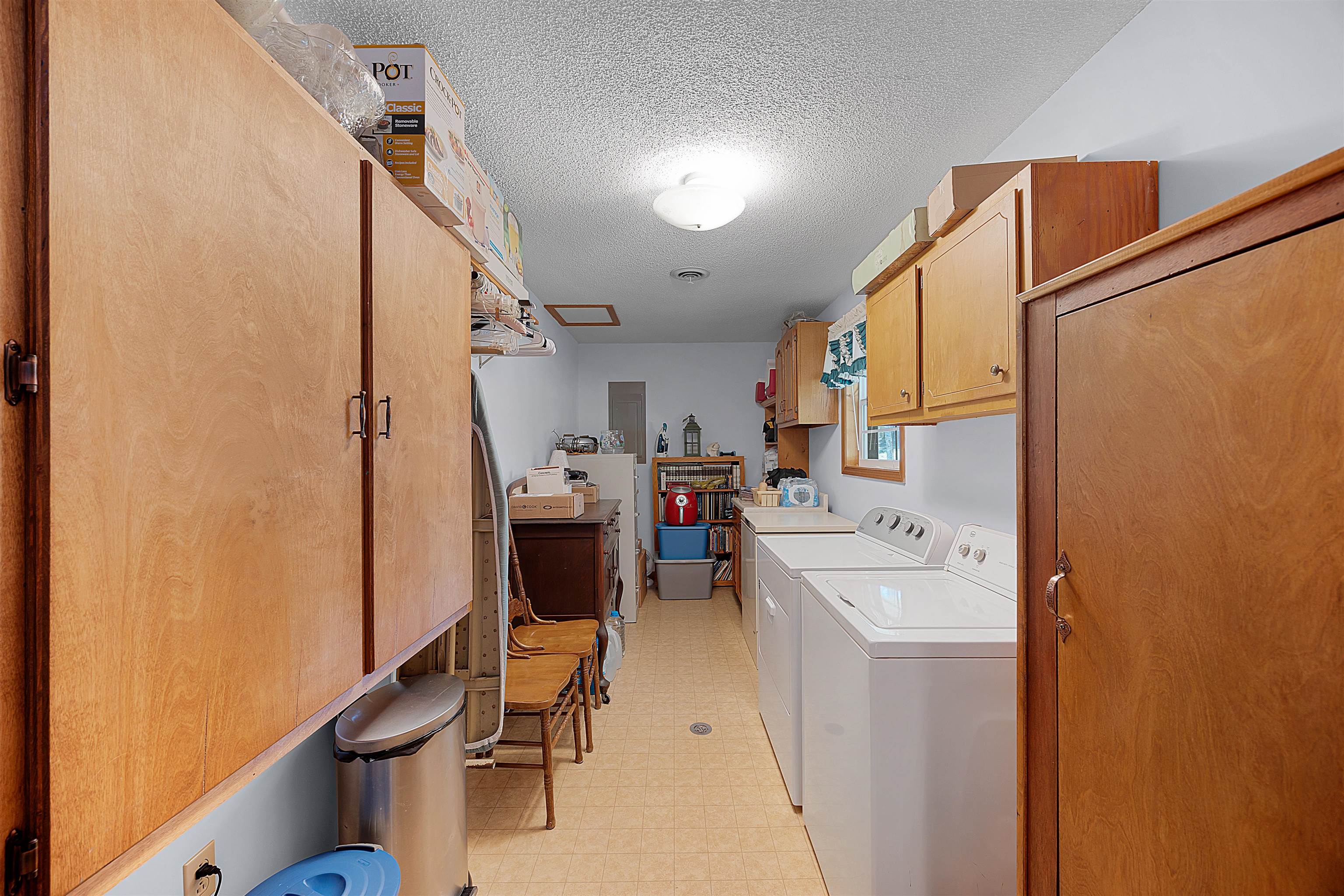 Clothes washing area with washer and dryer, a textured ceiling, and cabinets