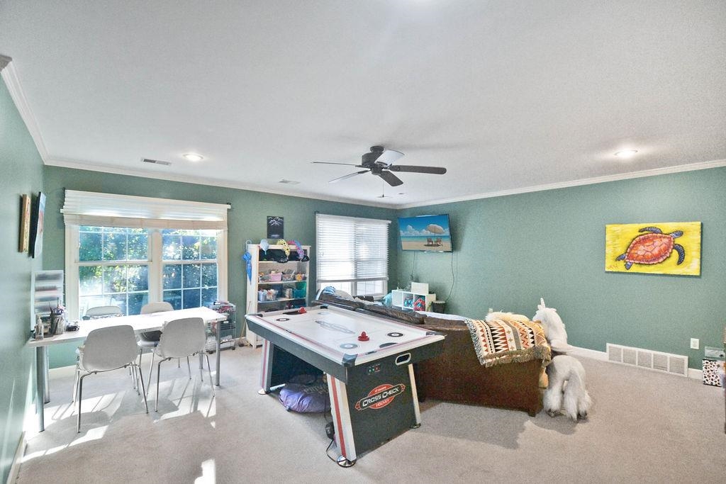 Rec room featuring a wealth of natural light, crown molding, light carpet, and ceiling fan