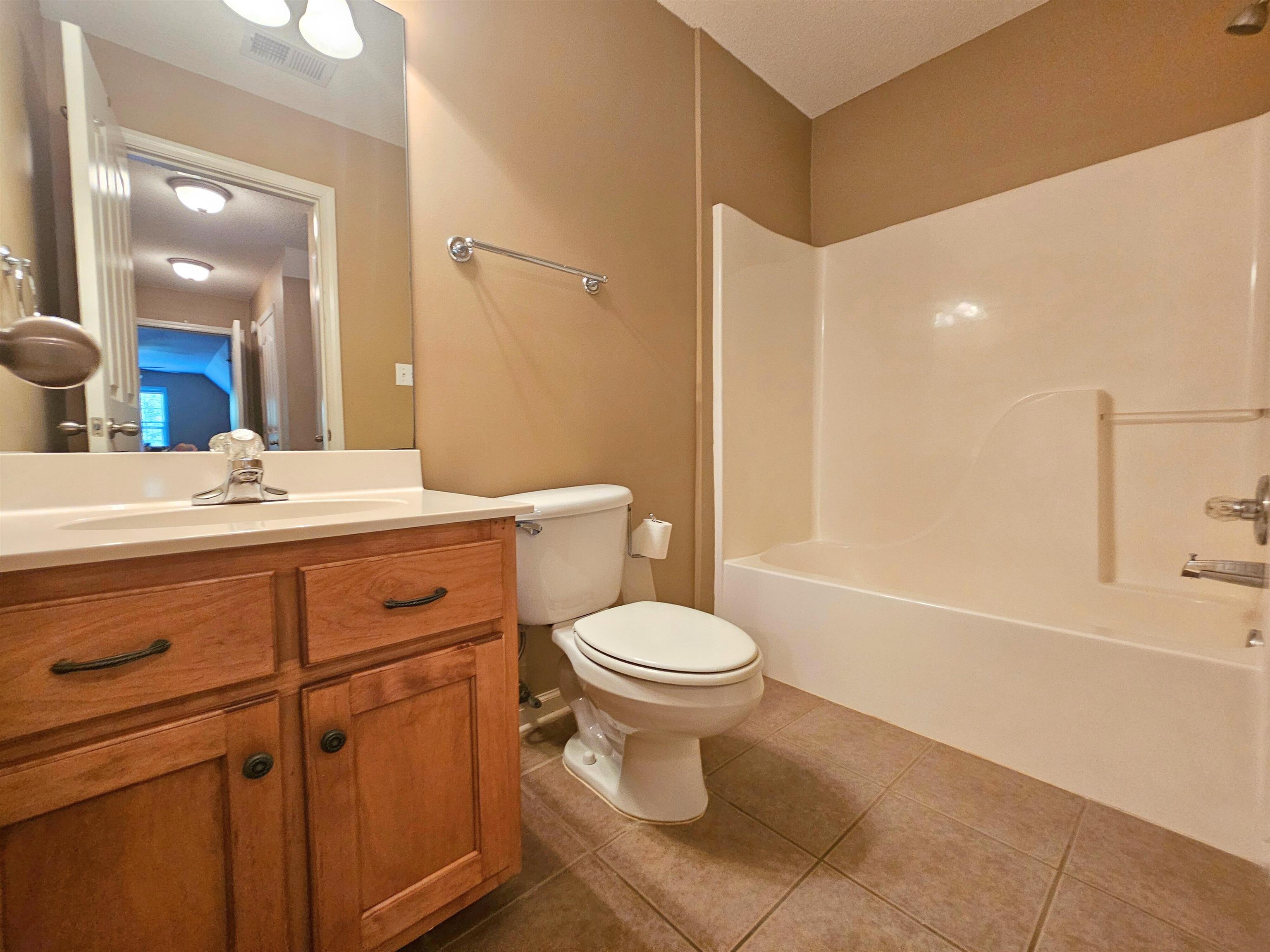 Full bathroom featuring vanity, bathing tub / shower combination, toilet, and tile patterned flooring