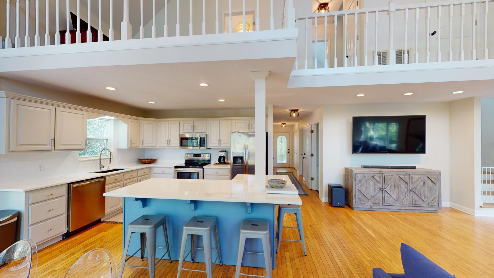 Kitchen with a towering ceiling, stainless steel appliances, a kitchen bar, and a kitchen island