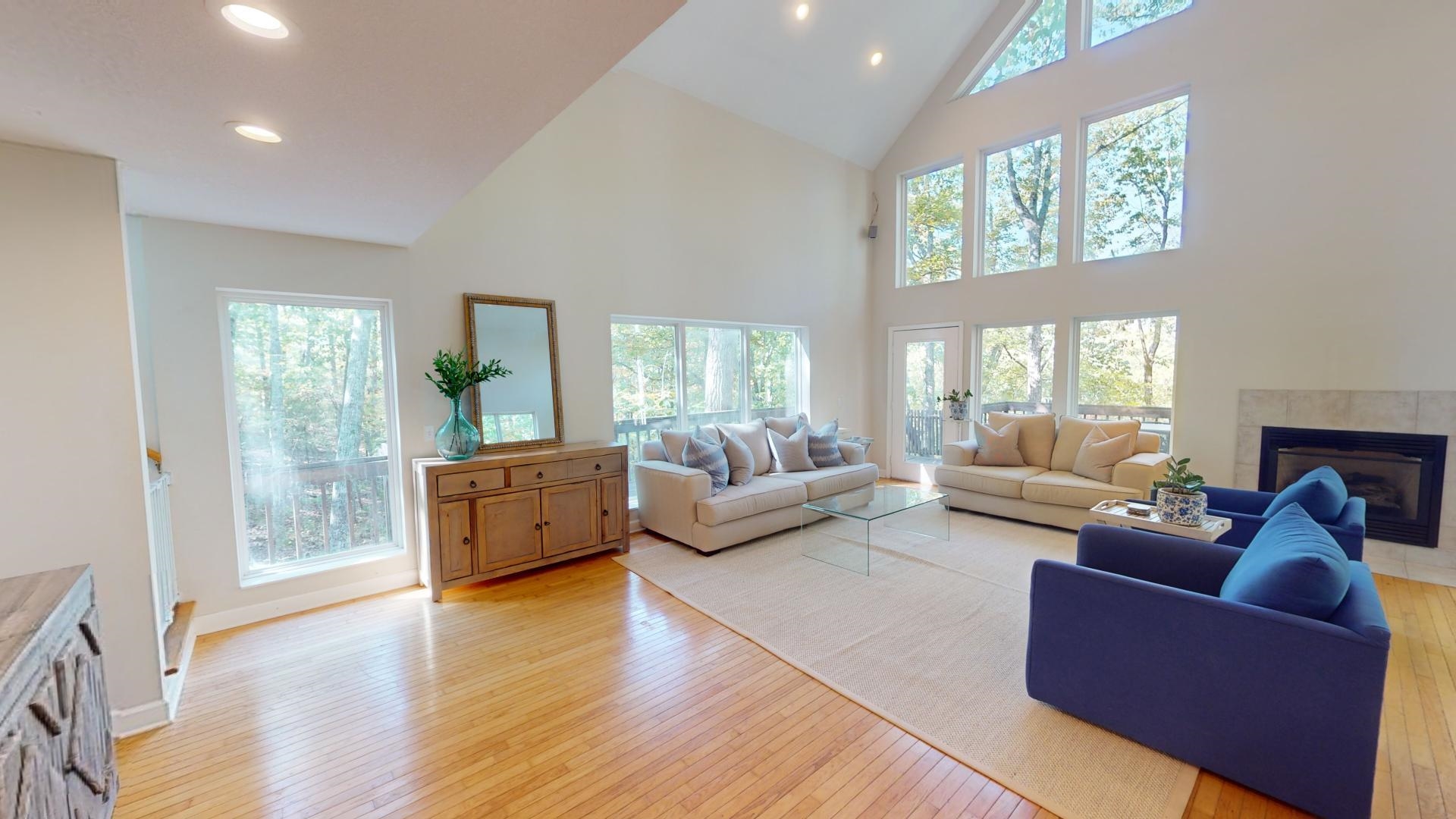 Living room with high vaulted ceiling, light wood-type flooring, and plenty of natural light