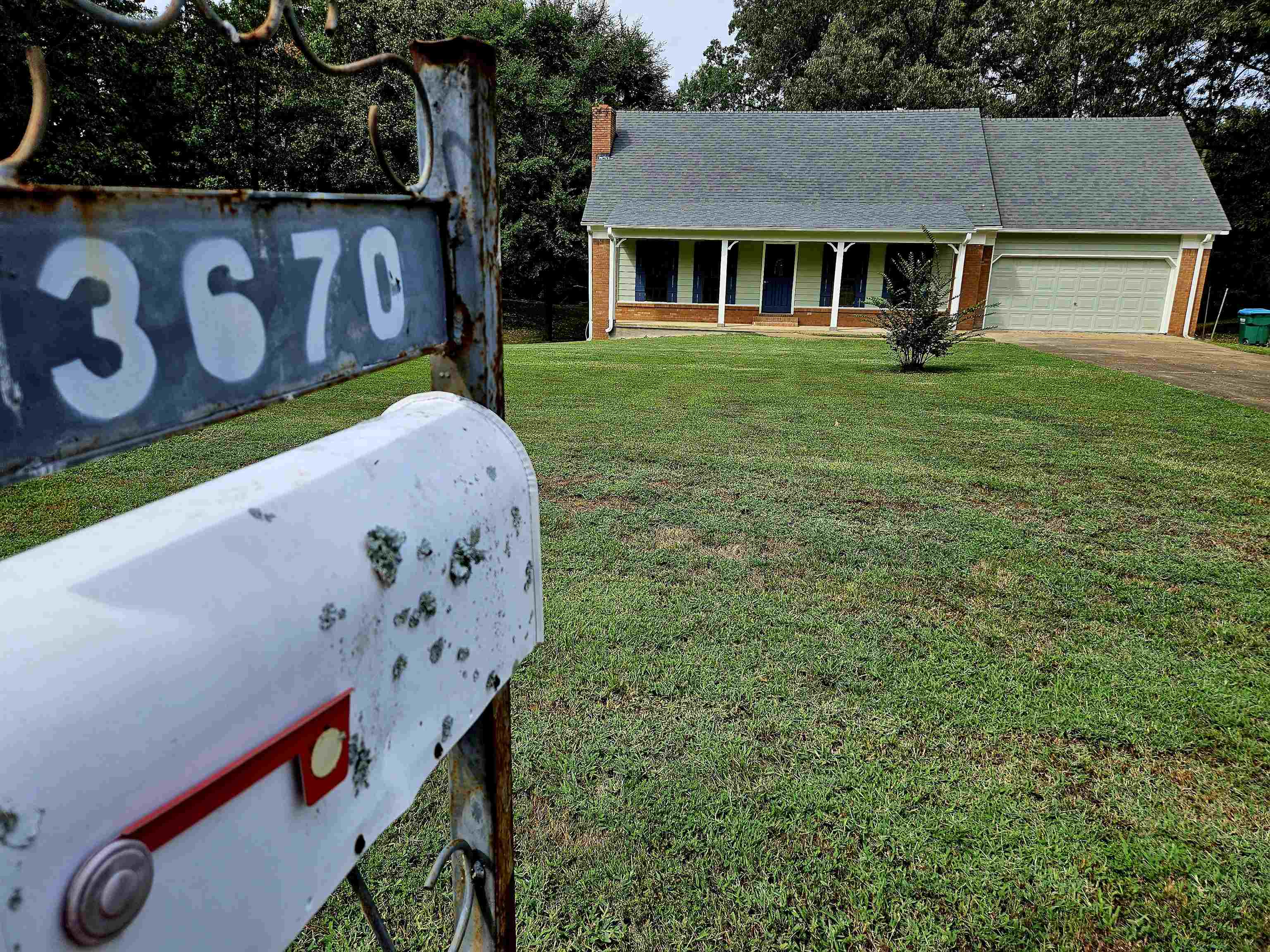 View of front of house featuring a front lawn, covered porch, and a garage