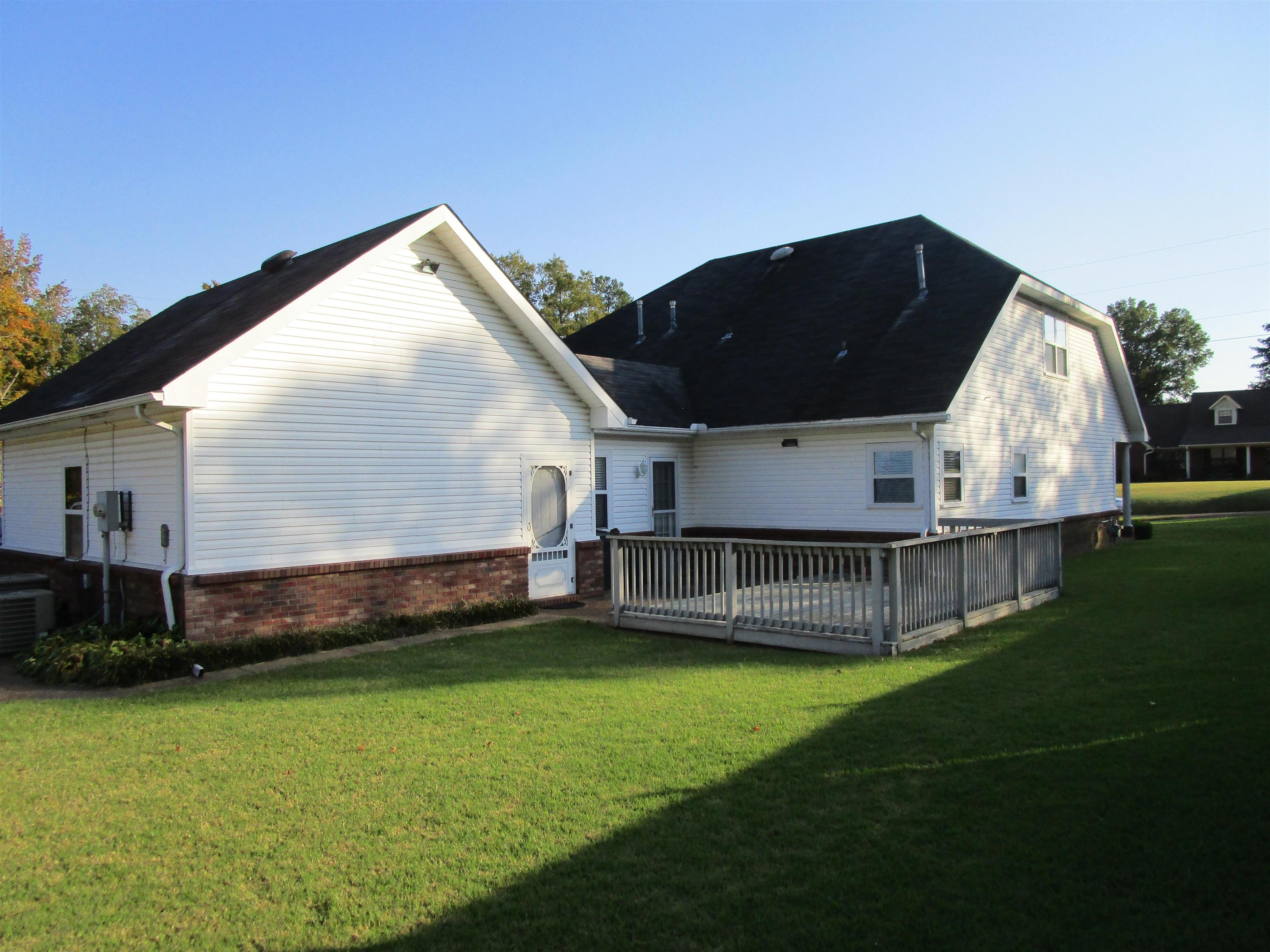 Back of house with a wooden deck and a yard