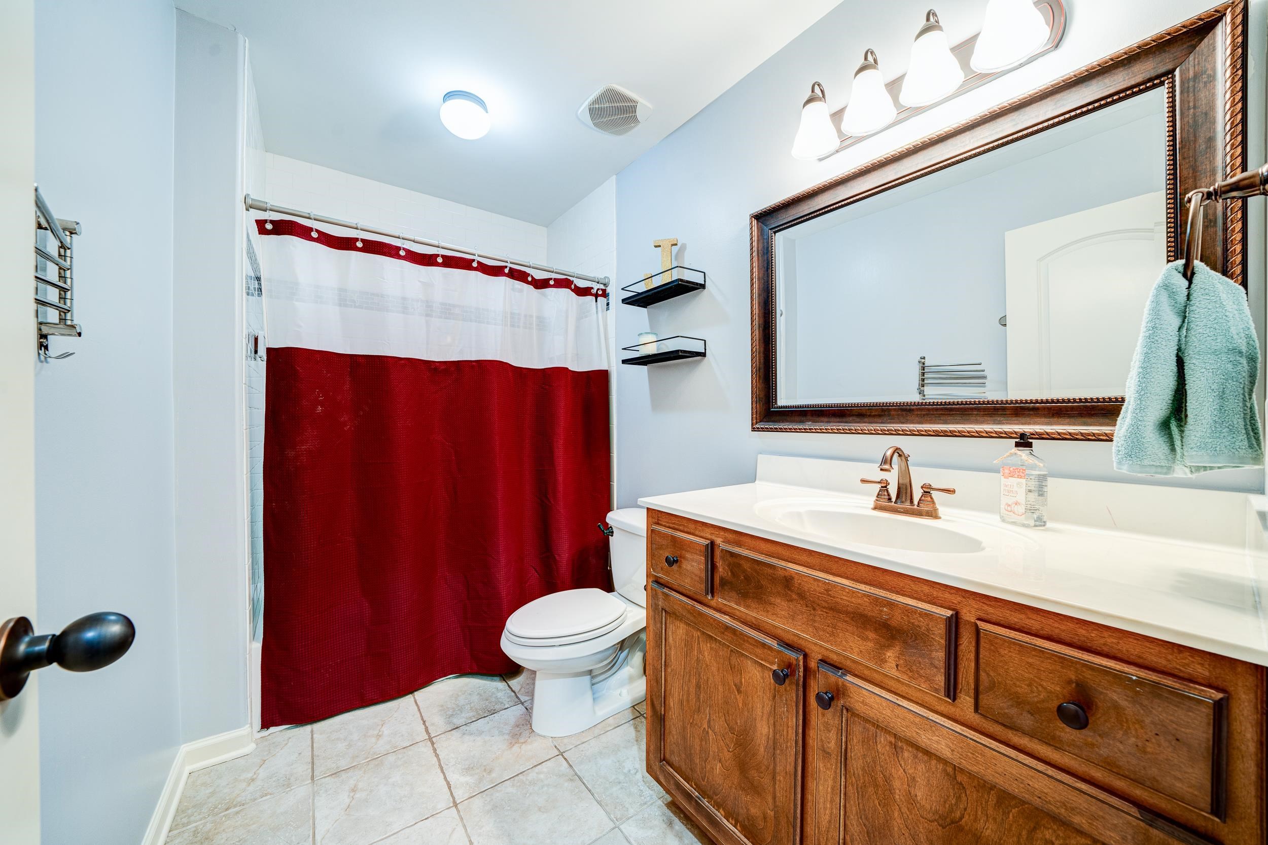 Bathroom featuring toilet, curtained shower, vanity, and tile patterned flooring