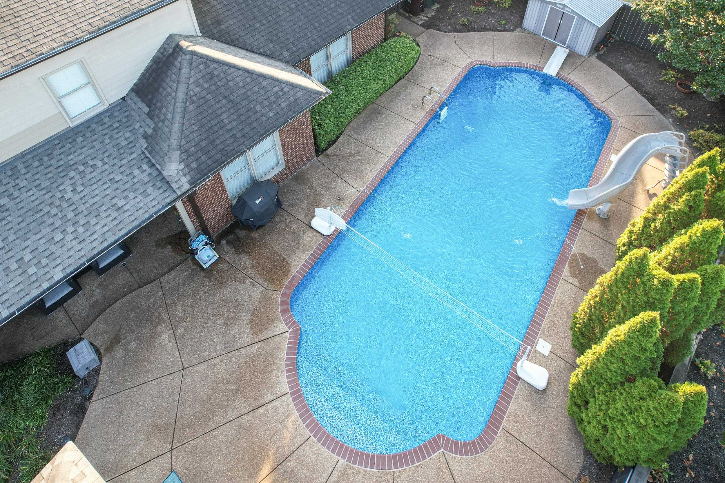 View of pool featuring a water slide, a storage shed, and a patio area