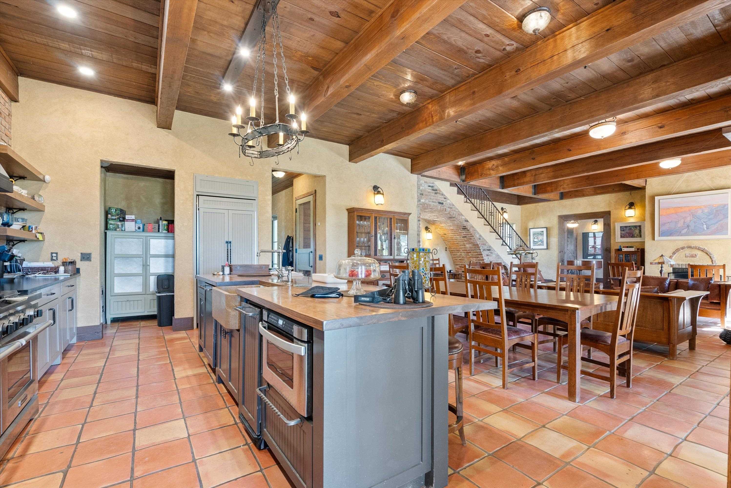 Kitchen featuring beam ceiling, an island with sink, wood ceiling, and stainless steel appliances