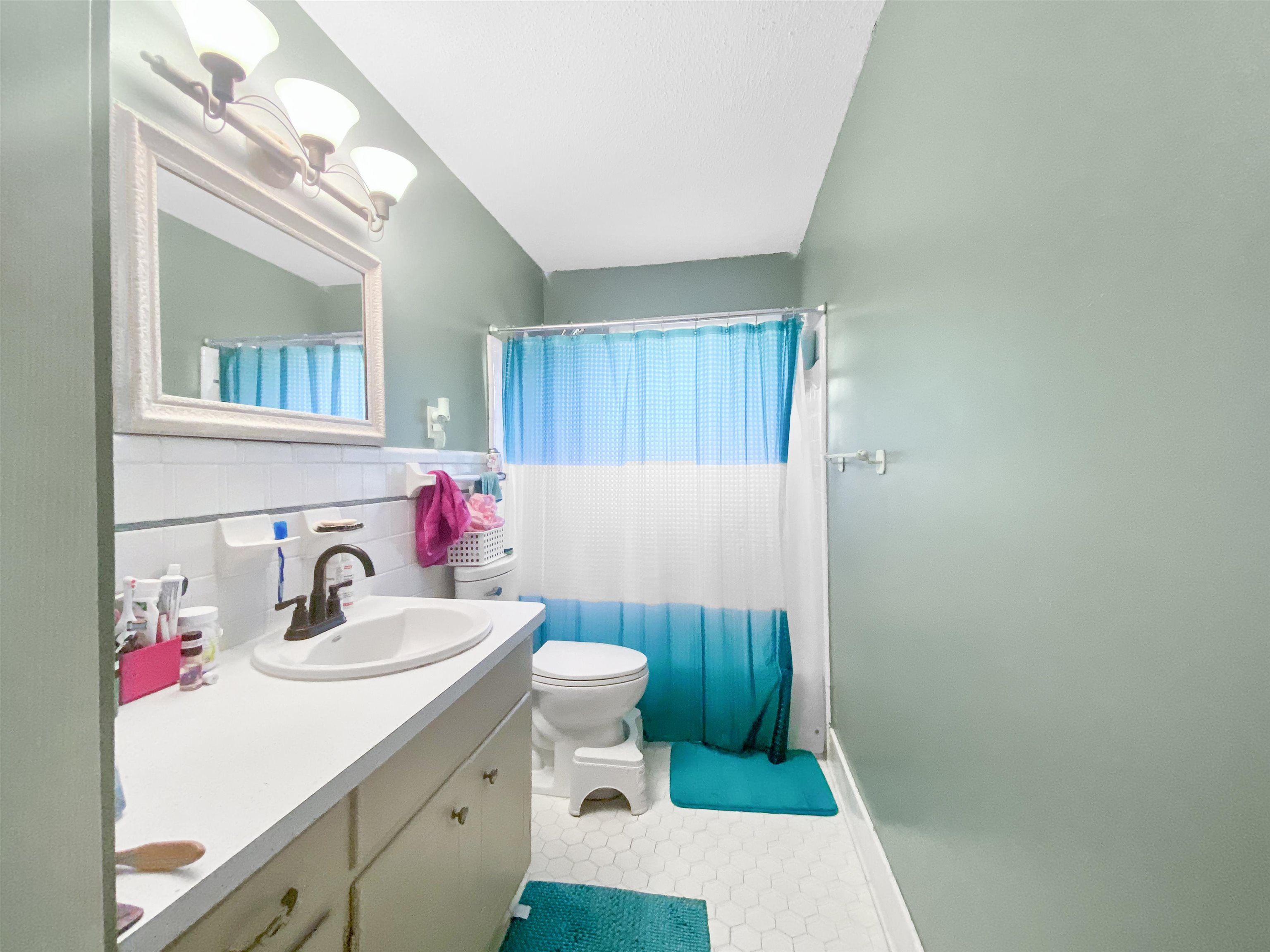 Bathroom with tile patterned floors, toilet, vanity, tile walls, and walk in shower