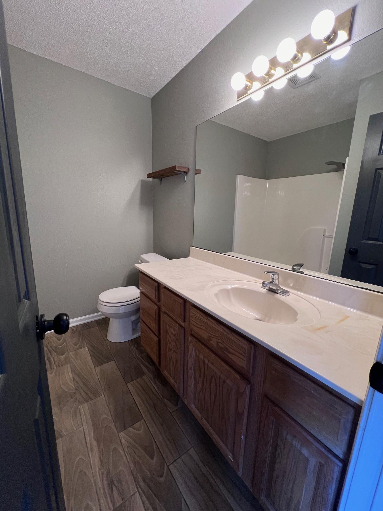 Bathroom featuring vanity, a textured ceiling, and toilet and tile floors