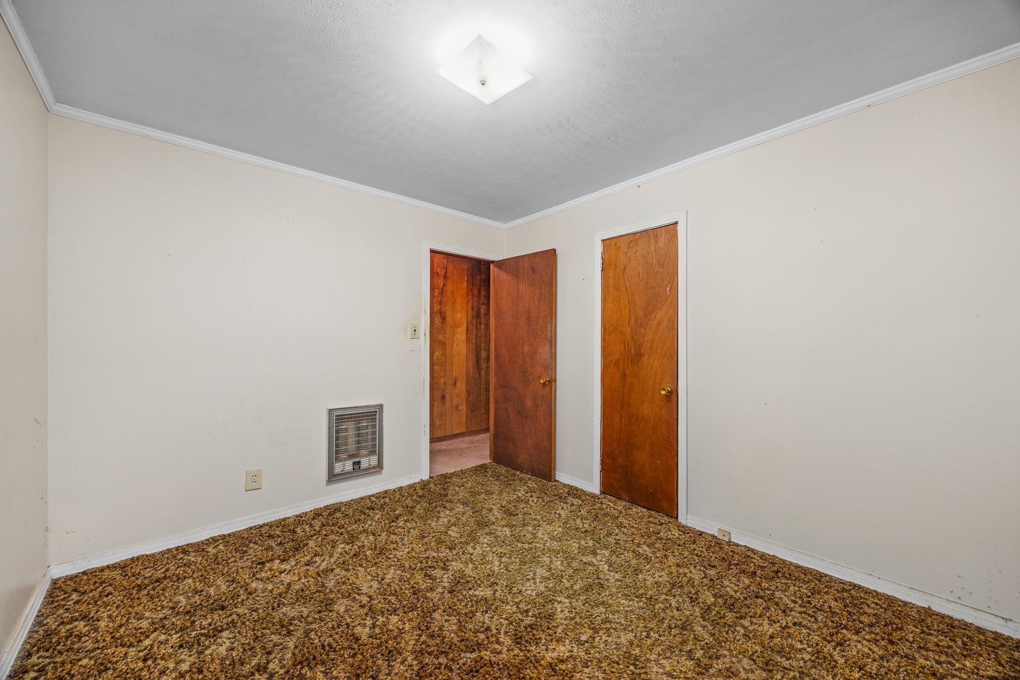 Carpeted empty room featuring ornamental molding and heating unit