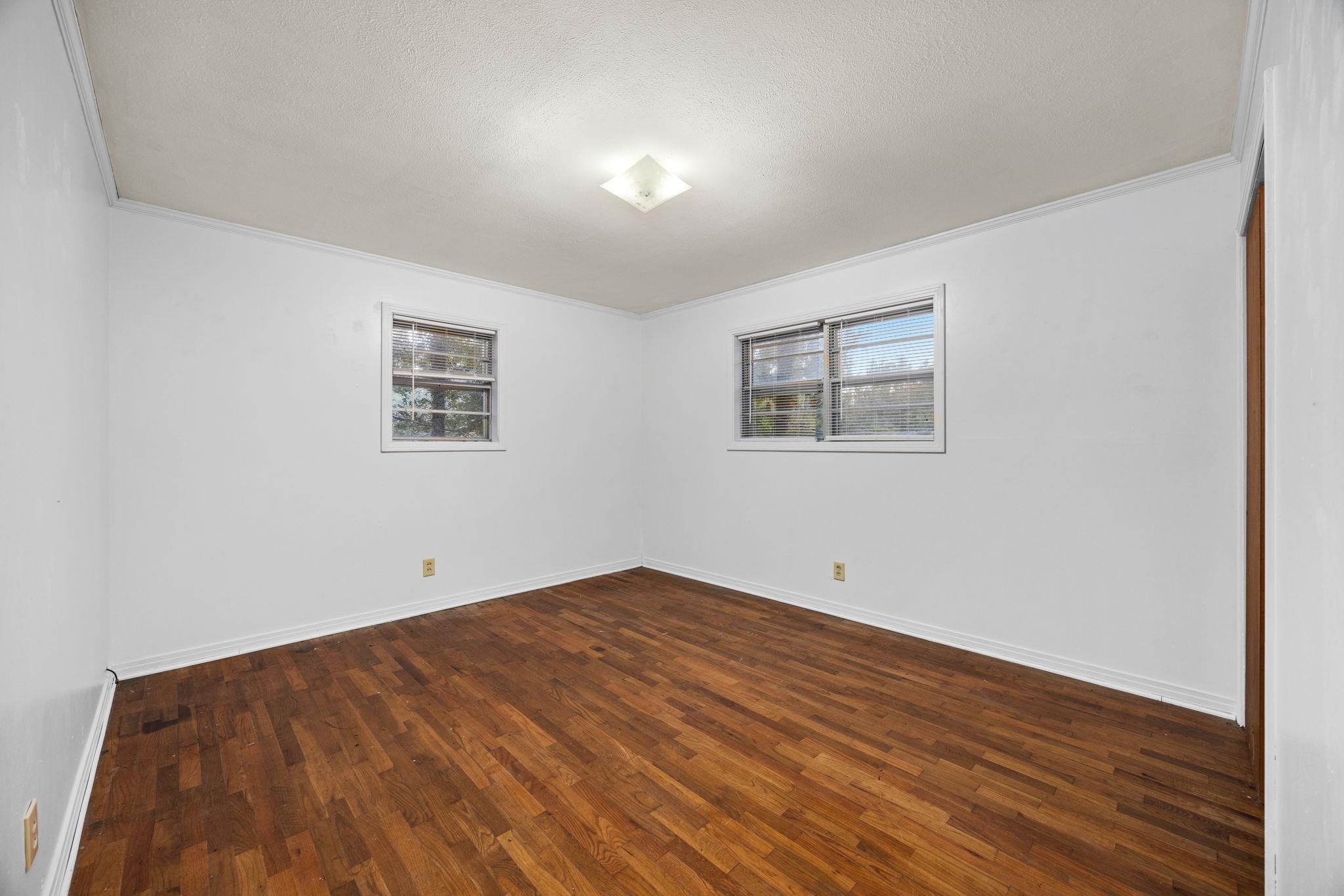 Unfurnished room with ornamental molding, a textured ceiling, and dark wood-type flooring