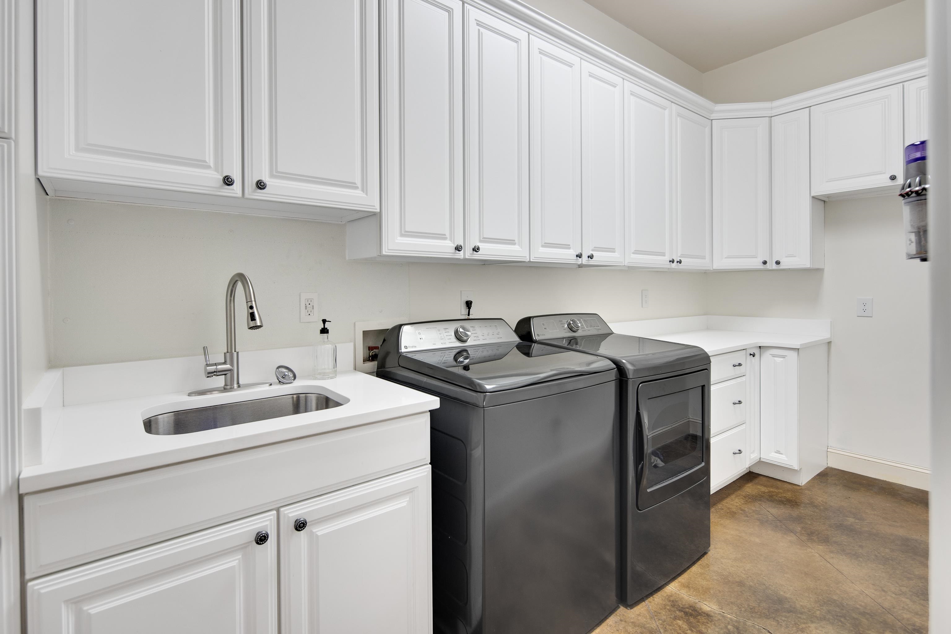 Laundry area featuring sink, washer and dryer, and cabinets