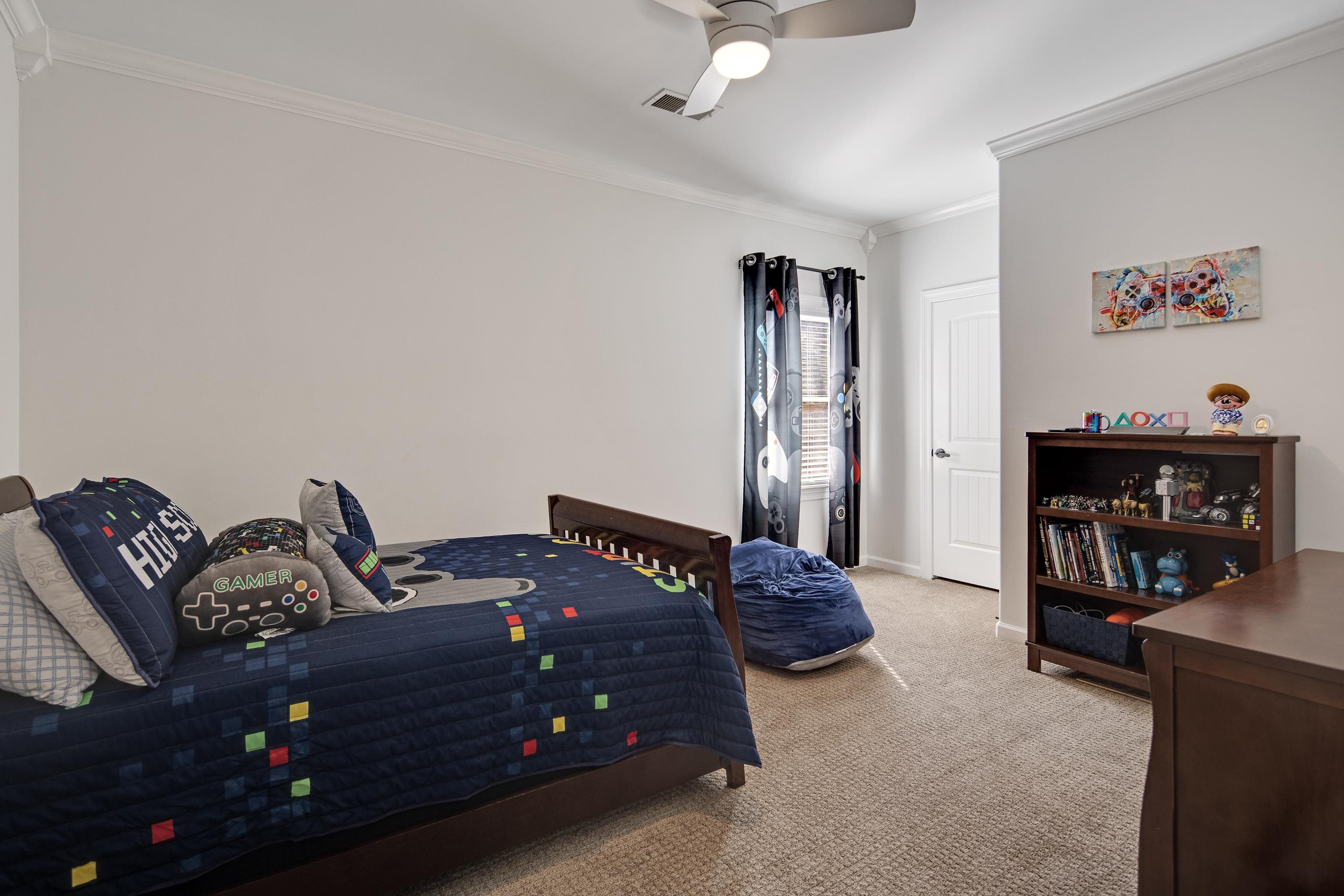 Bedroom with ceiling fan, crown molding, and light carpet