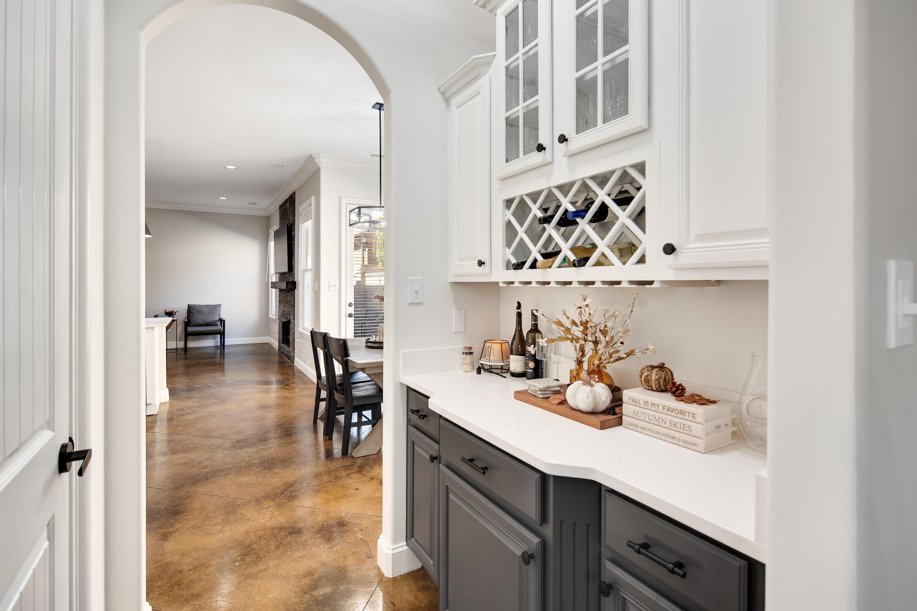 Bar featuring gray cabinets, crown molding, white cabinetry, and hanging light fixtures