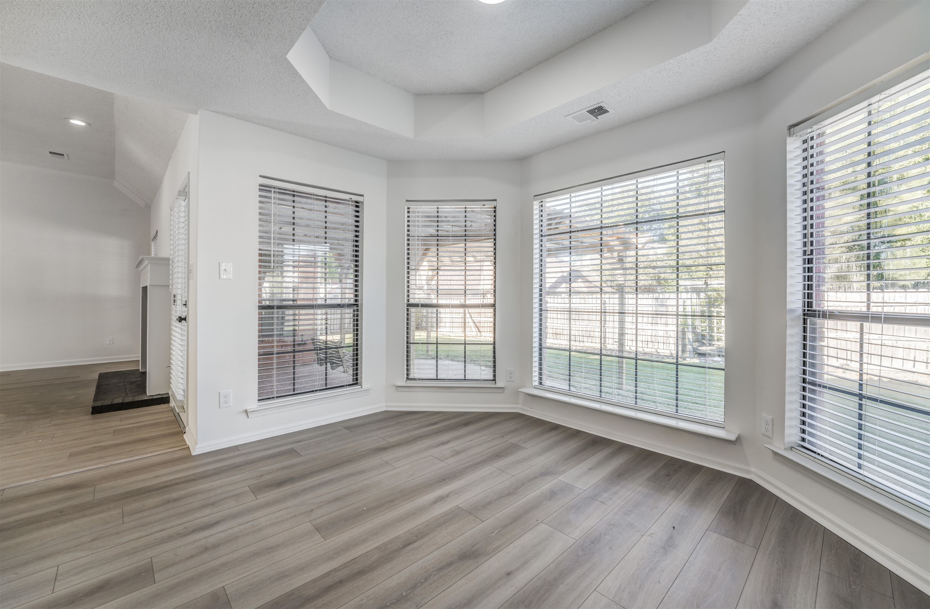 Unfurnished room with light hardwood / wood-style flooring, a textured ceiling, and a healthy amount of sunlight