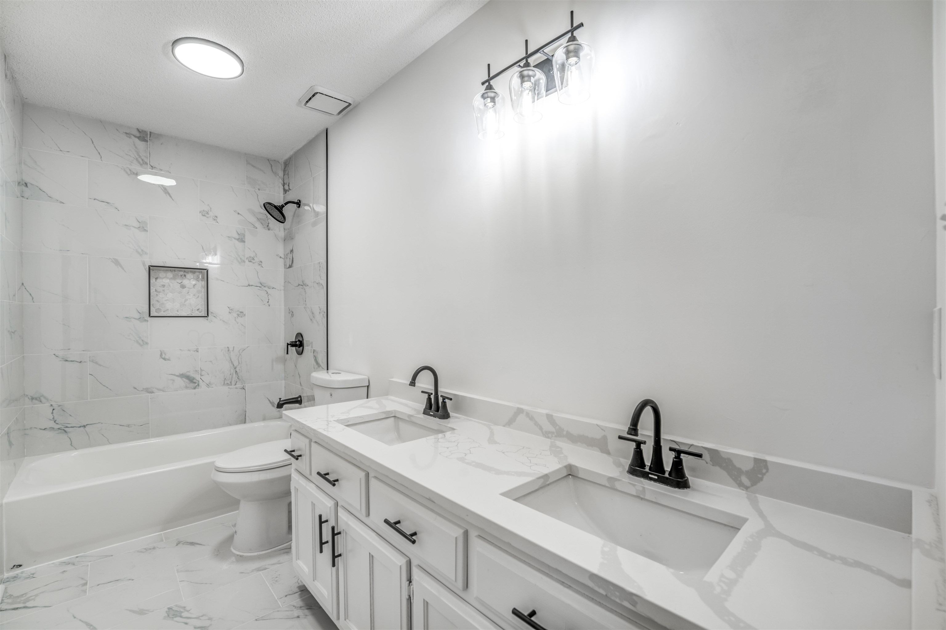 Full bathroom featuring vanity, toilet, tiled shower / bath combo, and a textured ceiling