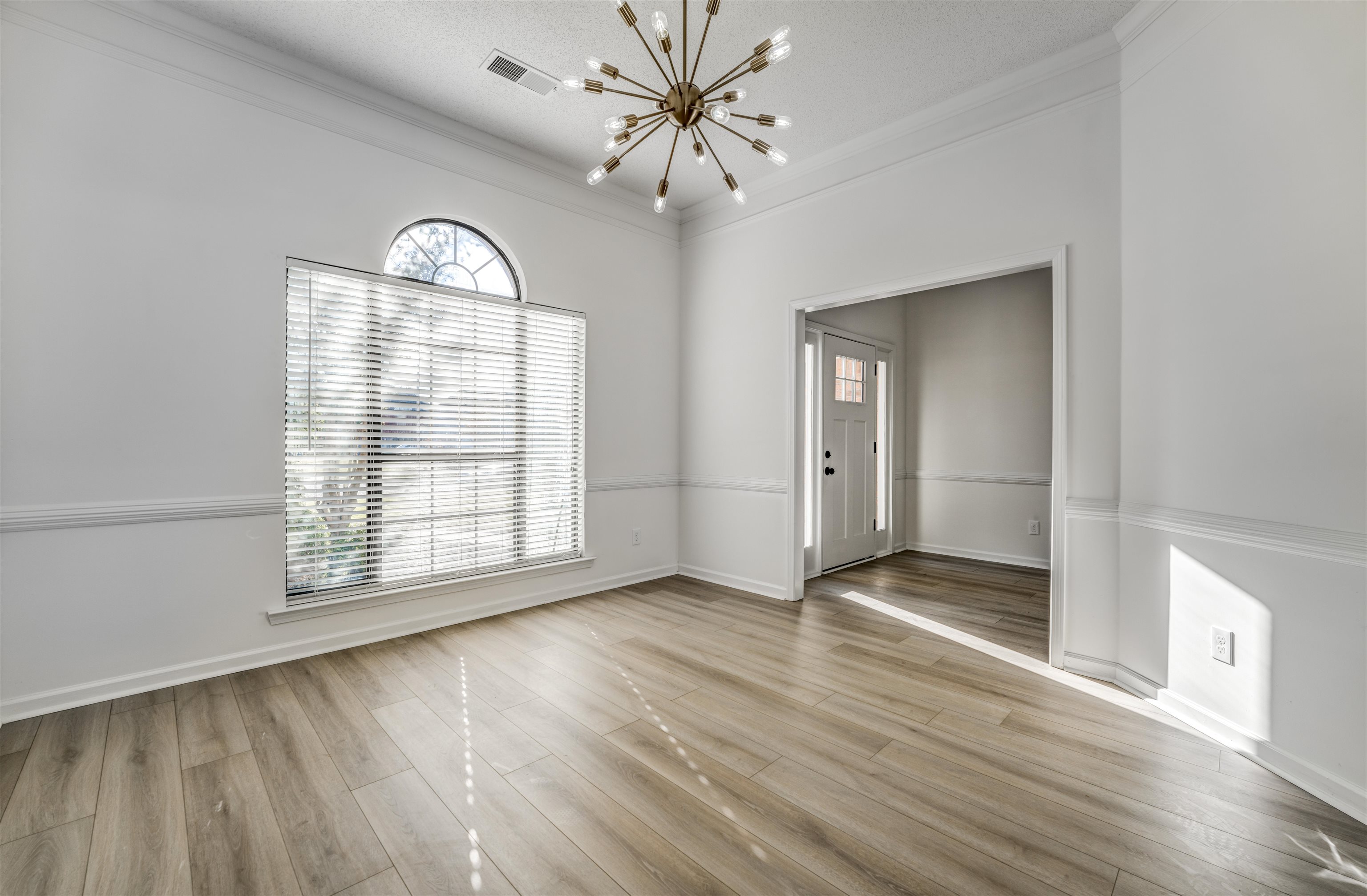 Spare room featuring crown molding, a textured ceiling, a chandelier, and light wood-type flooring