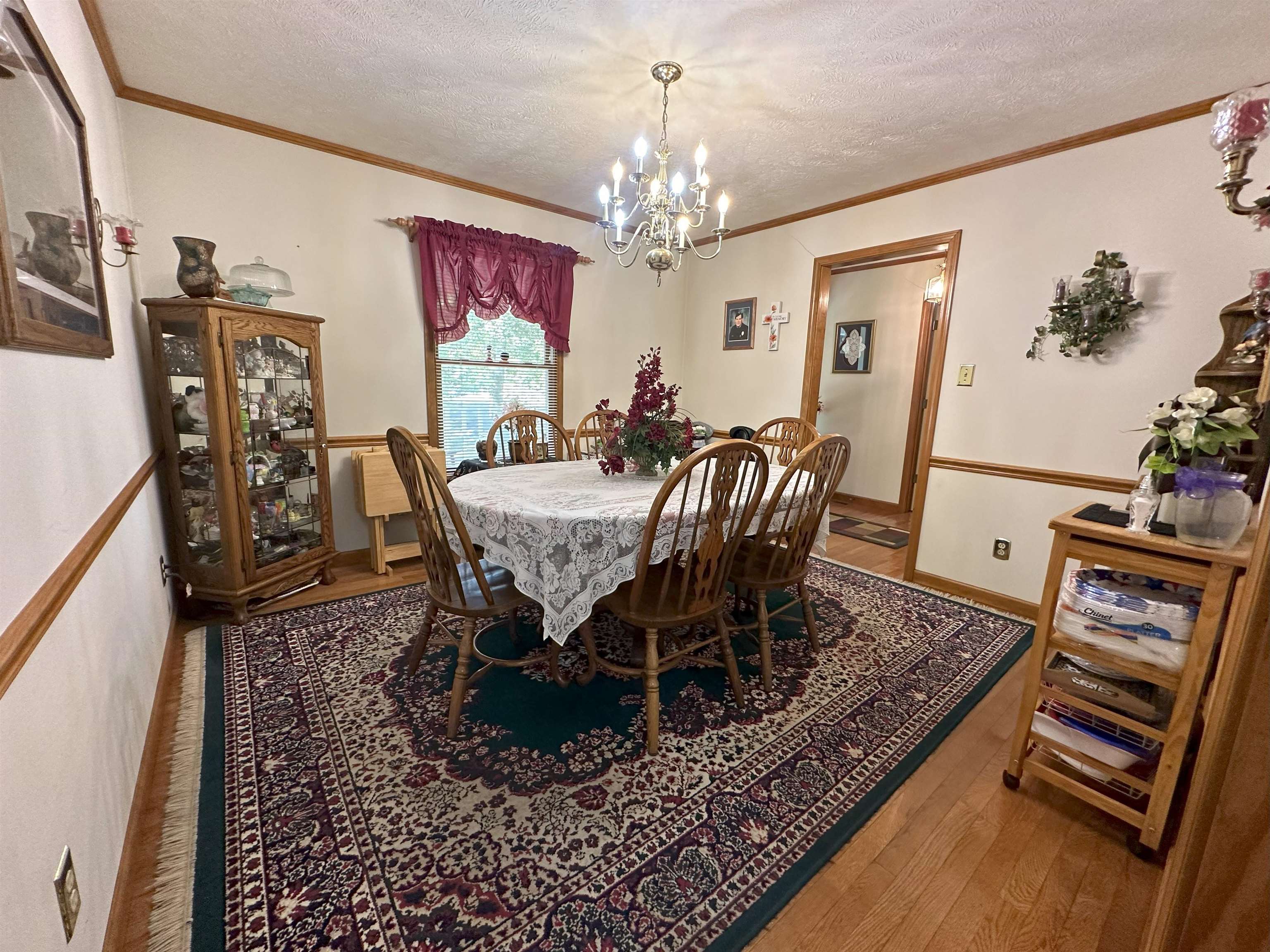 Dining area featuring ornamental molding, a notable chandelier, a textured ceiling, and wood-type flooring